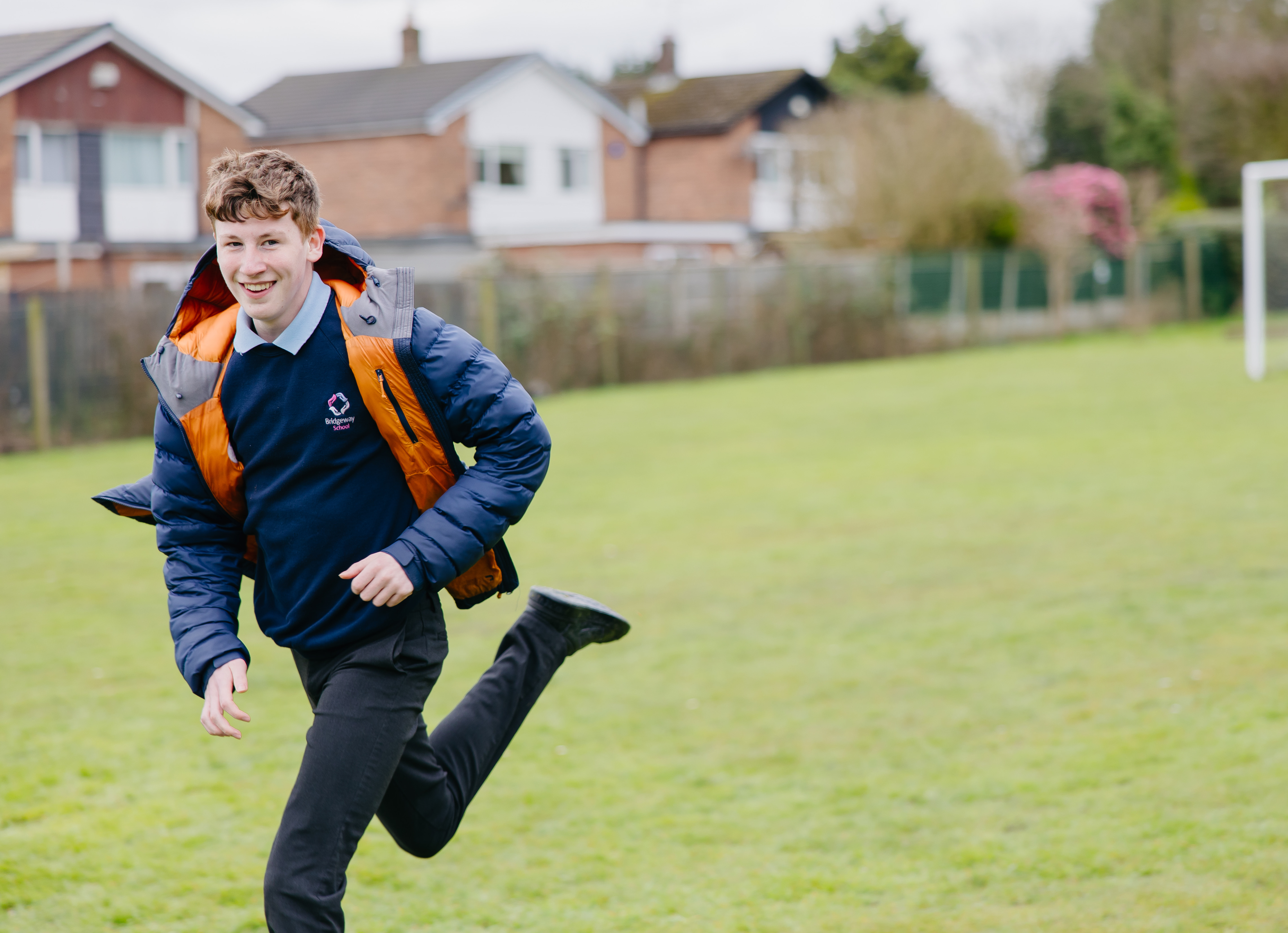 Boy running across school field while looking at the camera