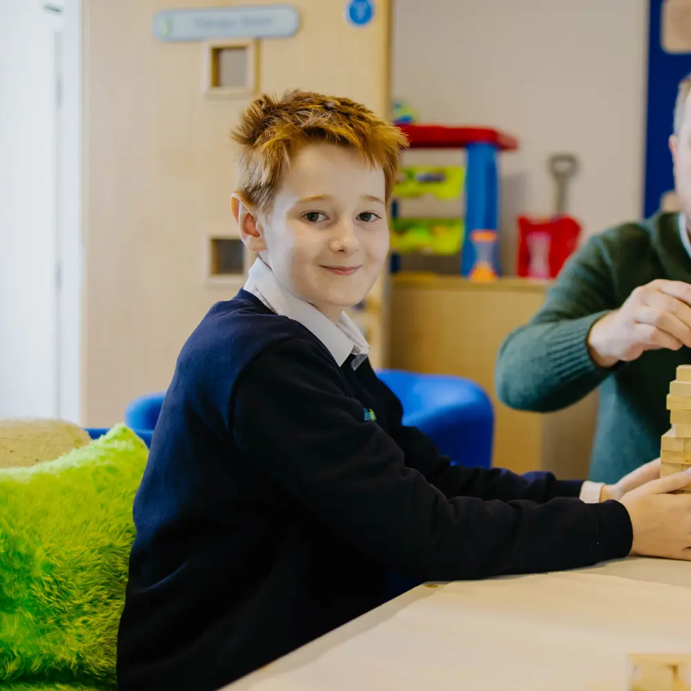 Young boy and and teacher from Millcourt playing Jenga in classroom