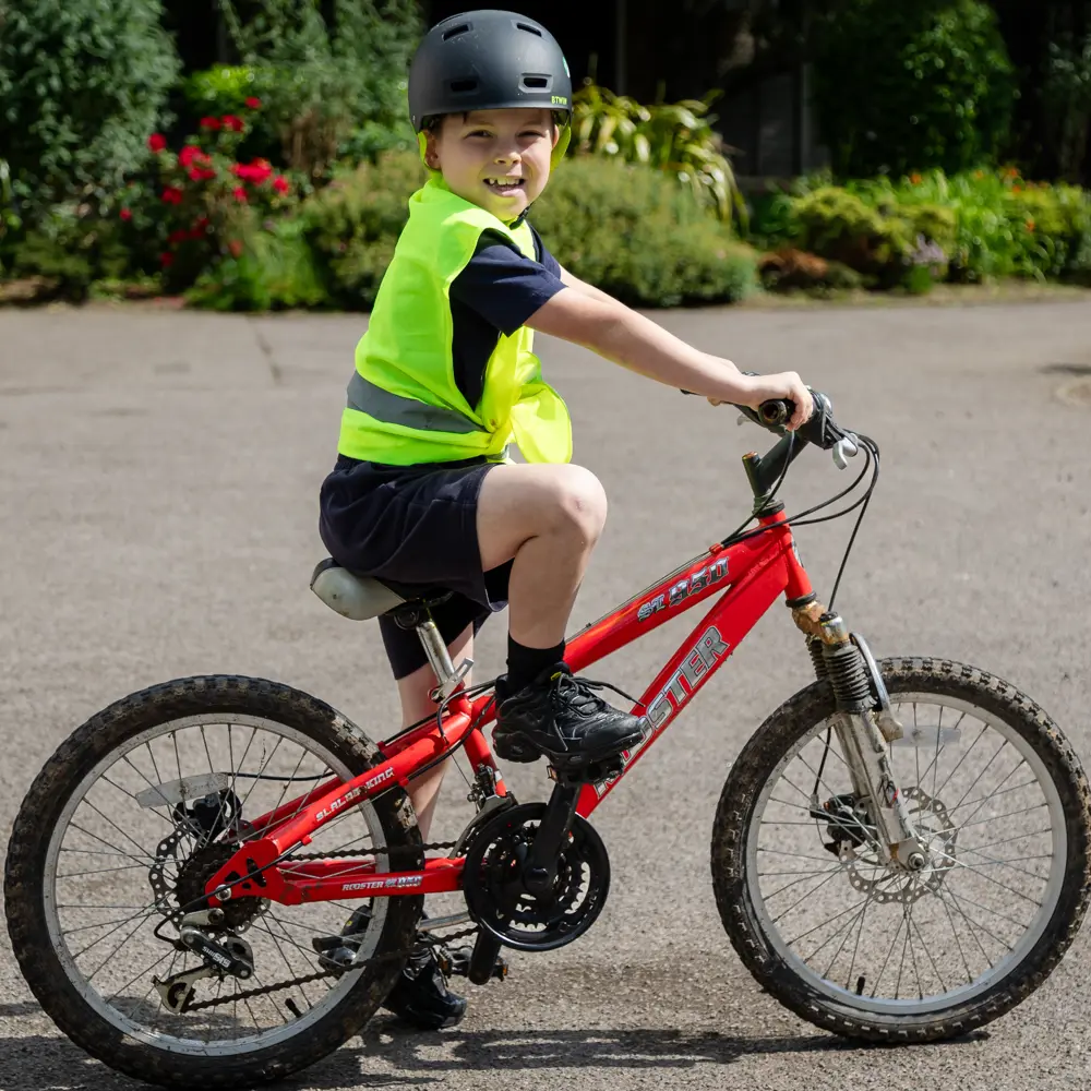 A young boy wearing a black helmet on a red bike at Bramley Hill School