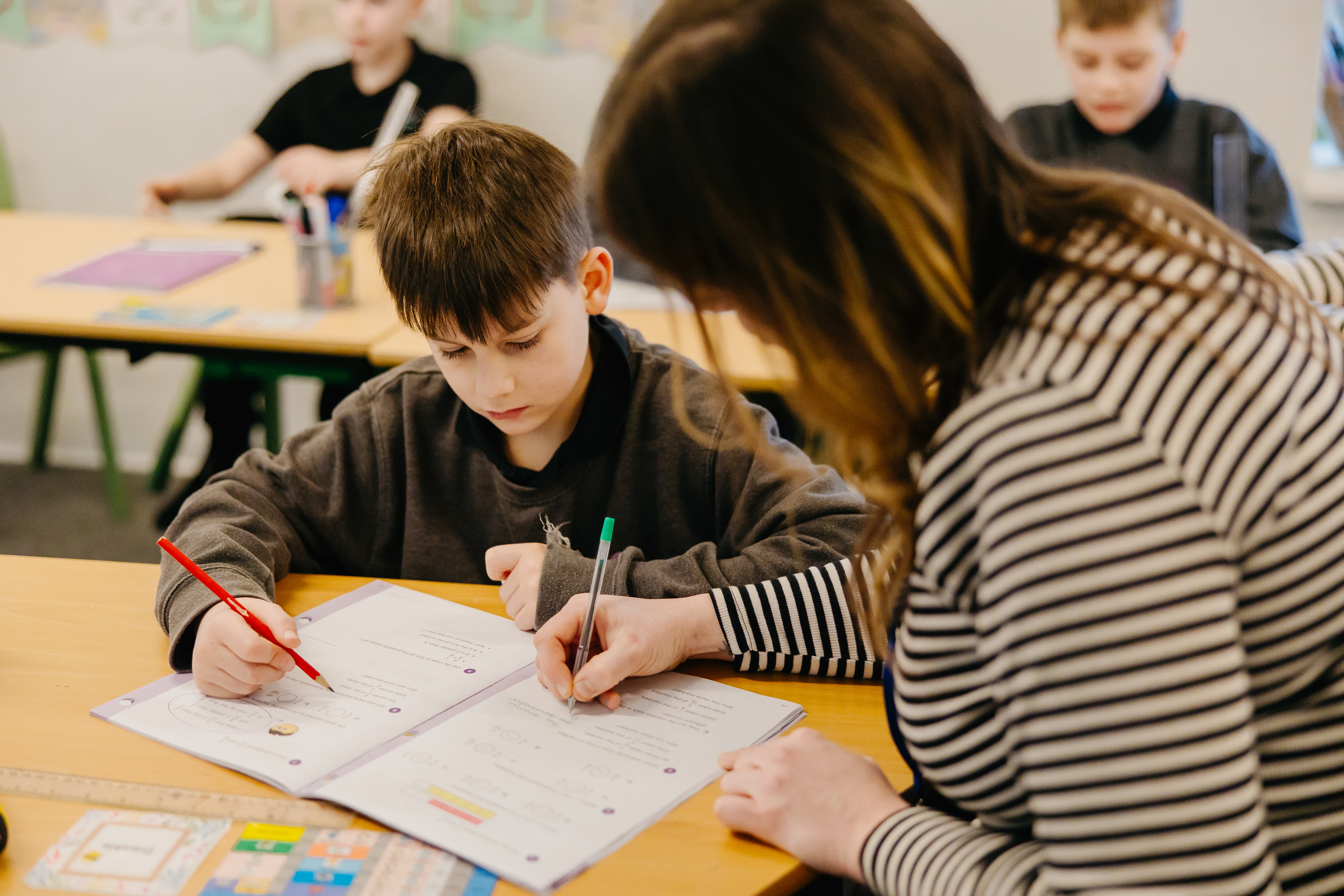 Teacher sat at pupils desk going through school work 
