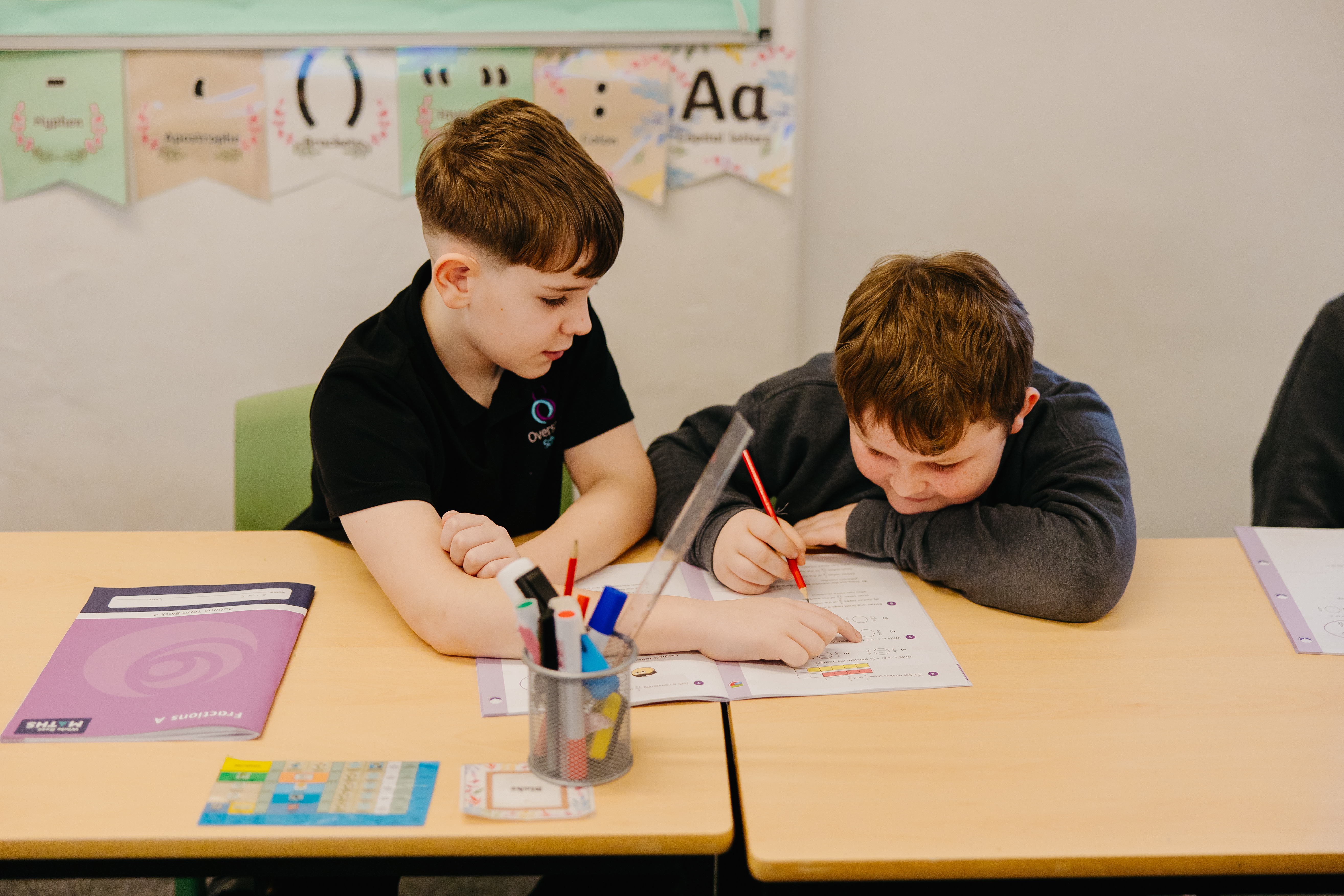 Two pupils sat together going through a worksheet in the classroom