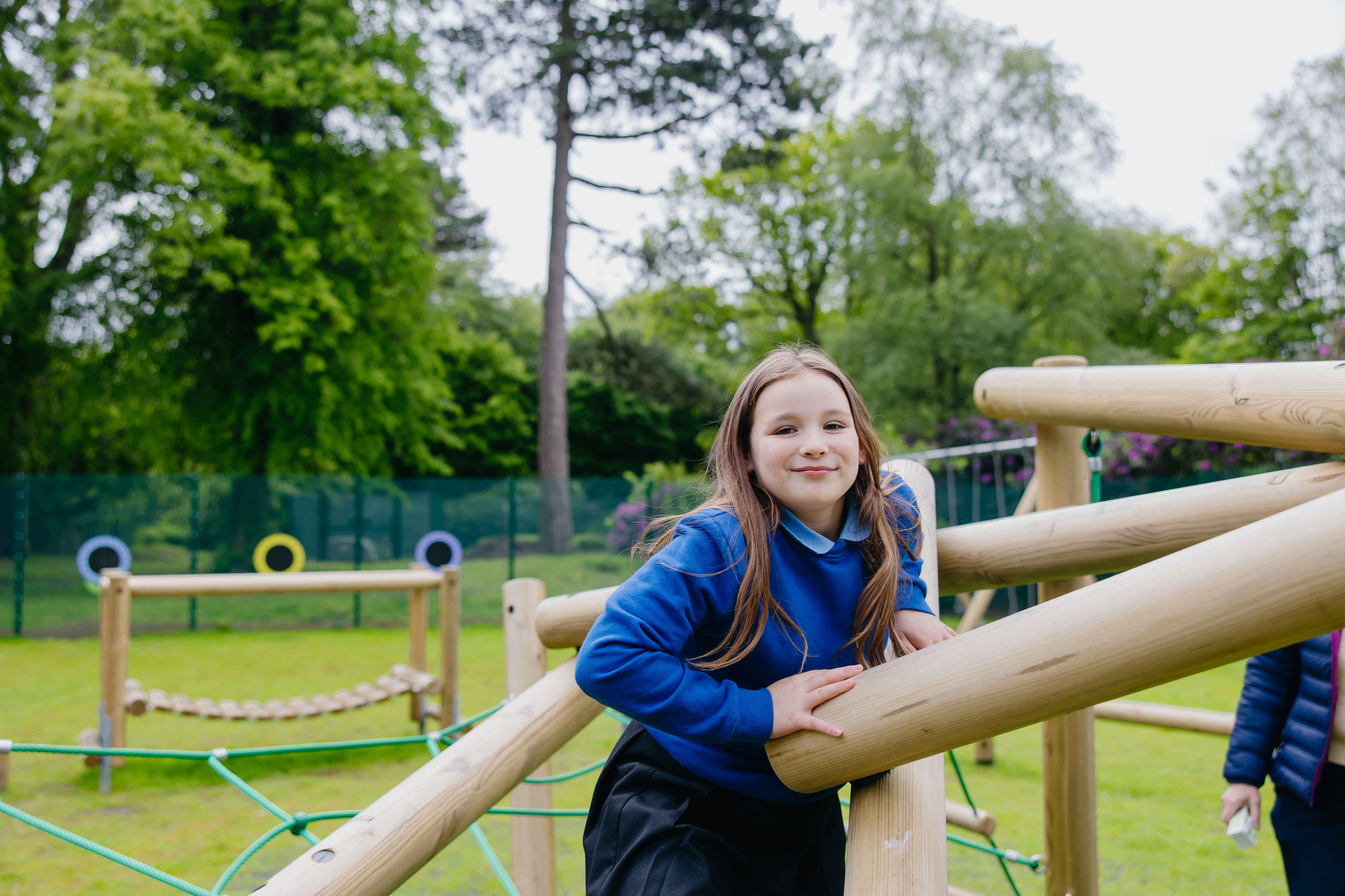 Girl climing on wooden play frame outside