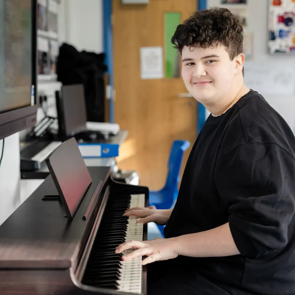 A young boy at Dovetree School playing the piano