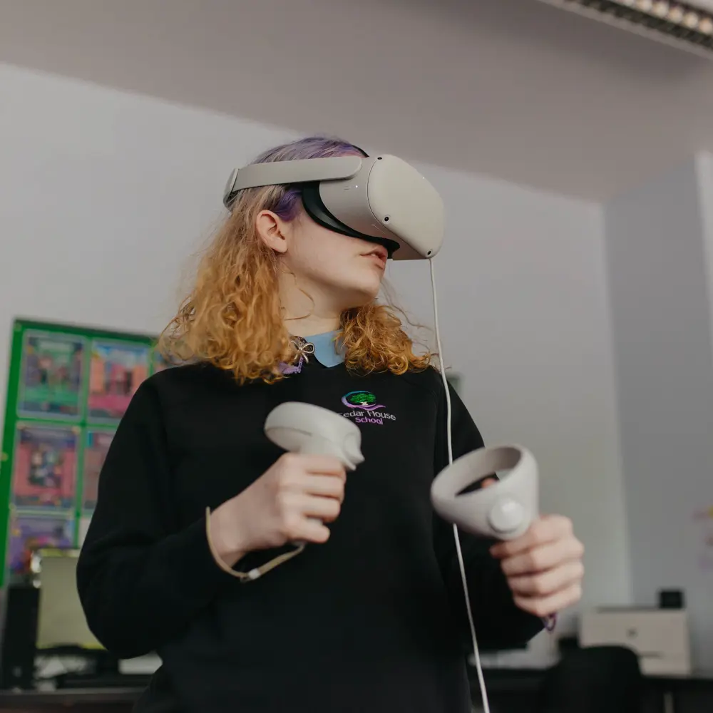 A young girl in a black uniform wearing a VR headset at Cedar House School