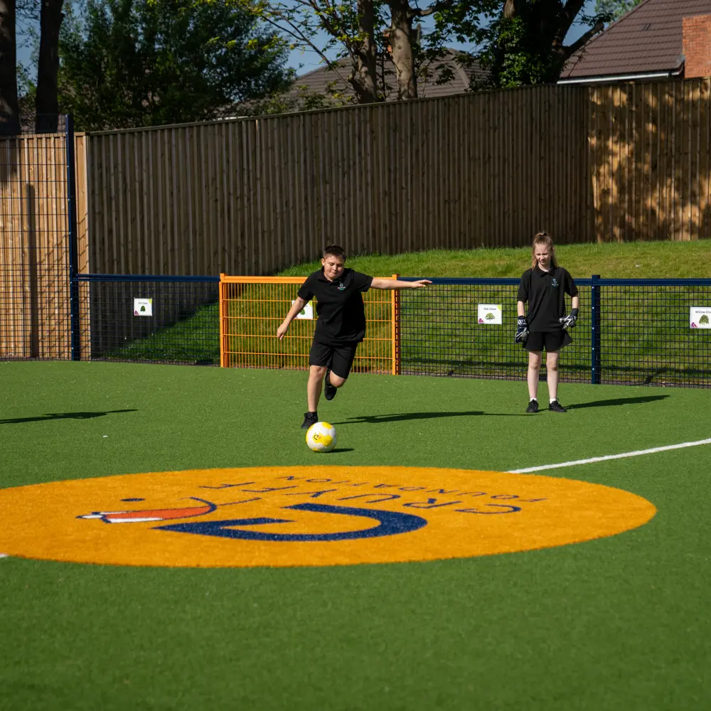 Three boys at Bescot Hall School playing football on the Cruyff Court