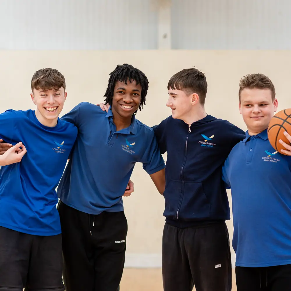Four pupils at Chilworth House Upper School in the gym hall laughing at the camera