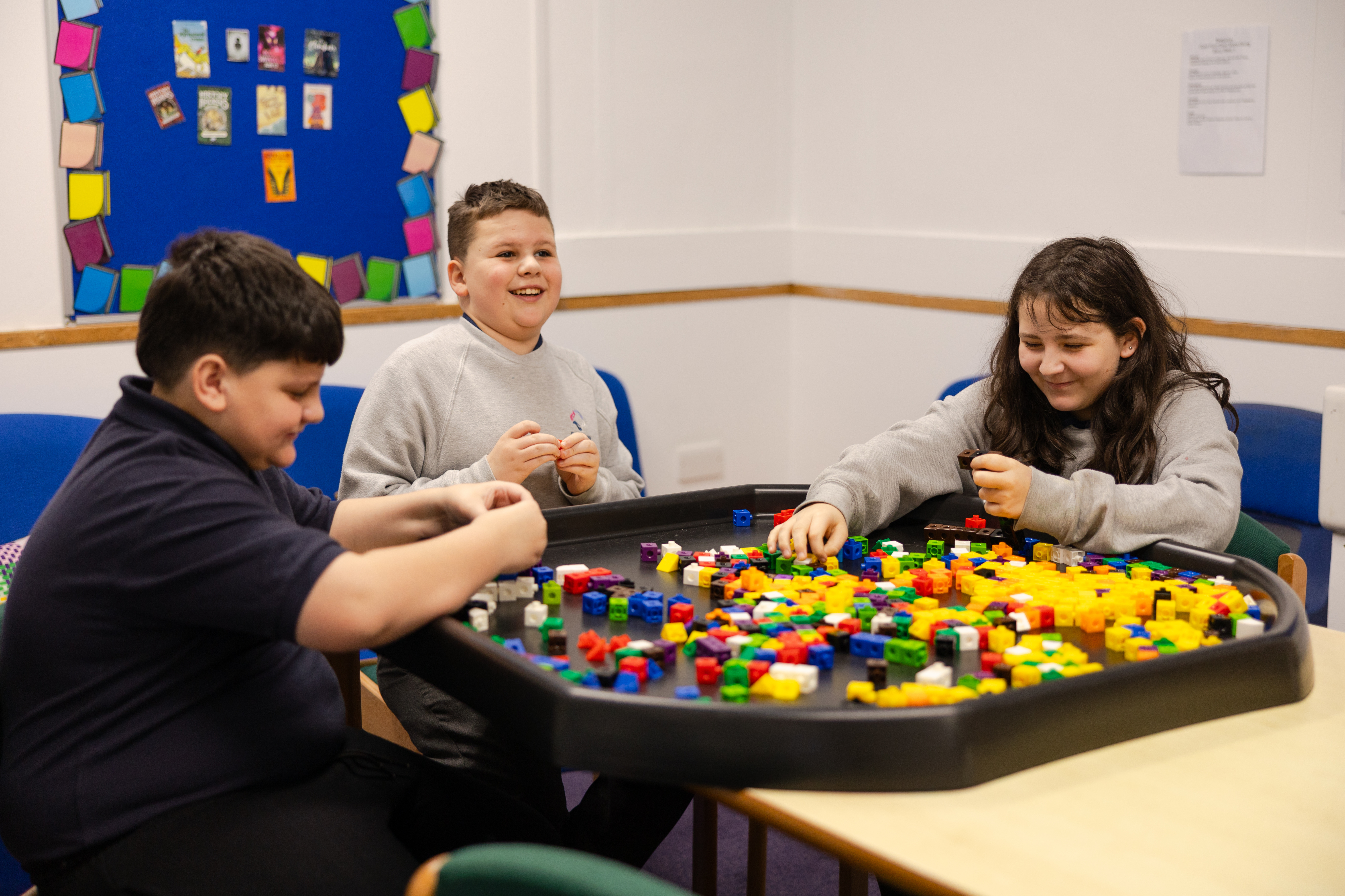 Three children playing with blocks round a table