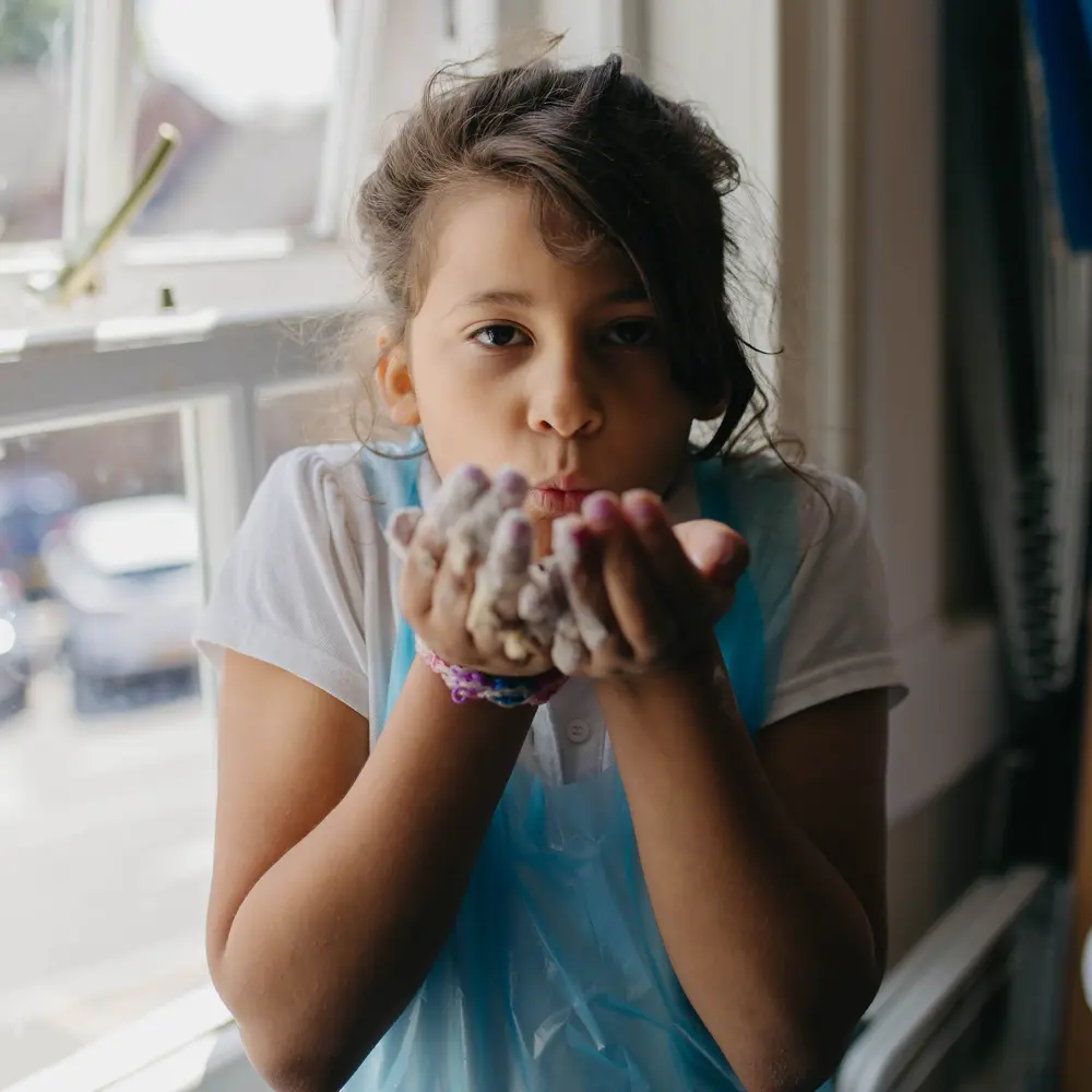 A young girl at Hall Cliffe Primary School wearing an apron with flour on her hands
