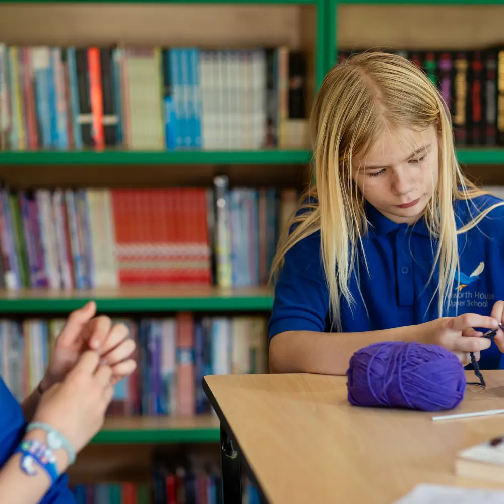 Two pupils at Chilworth House Upper School sitting in a classroom learning how to crochet