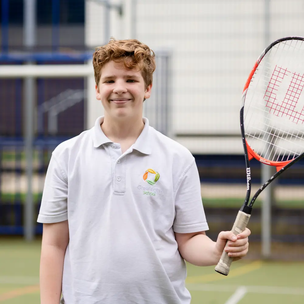 Smiling boy holding a tennis racket at Greenholm School