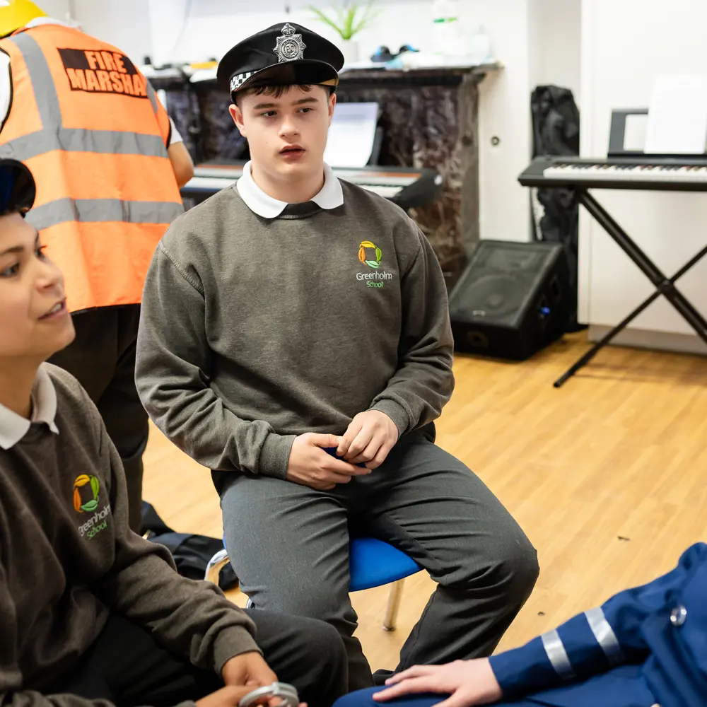 Two male pupils from Greenholm School wearing police hats sitting next to each other