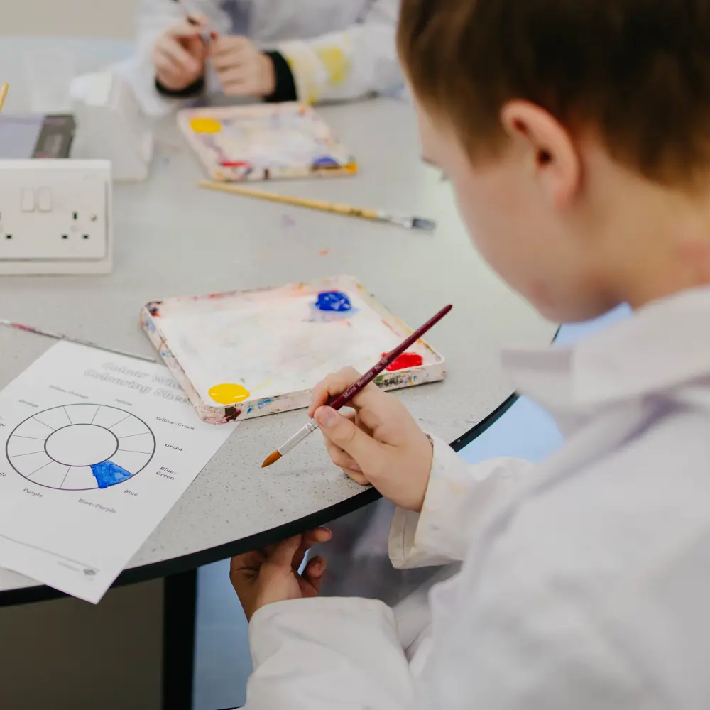 A pupil painting at Cumberland School in a classroom