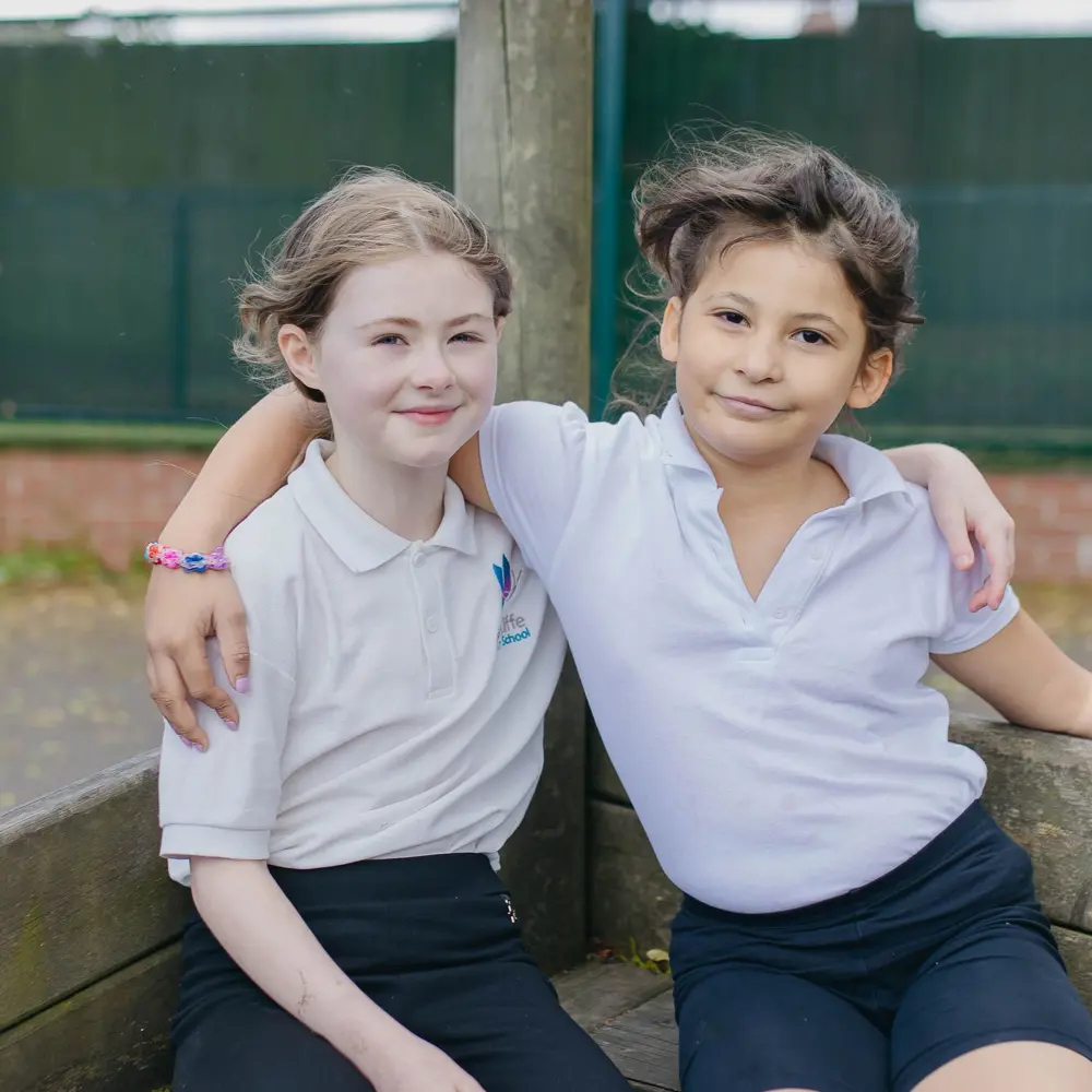 Two girls at Hall Cliffe Primary School sat in a wooden boat in the play ground with their arms around each other