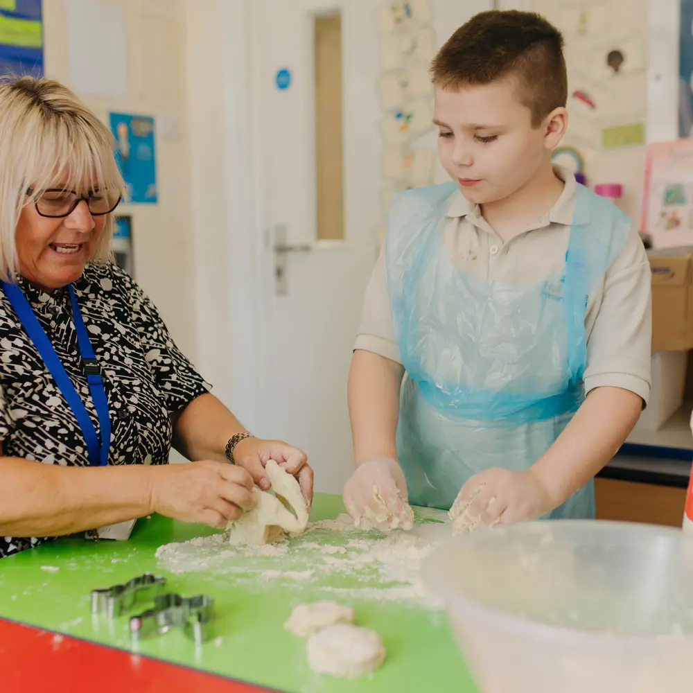 A young boy at Hall Cliffe Primary School baking with a member of staff