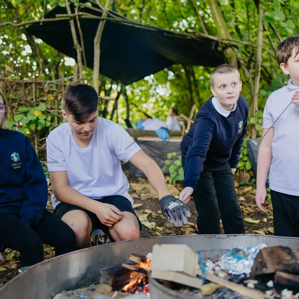 Four pupils at Millcourt School outside in the forest school area