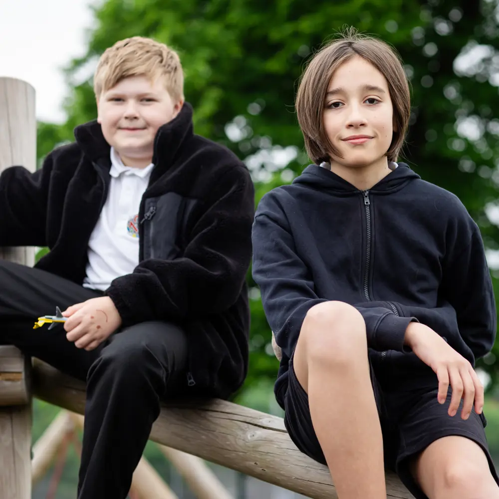Two young boys from Luxborough Court School sat on top of a climbing frame and smiling