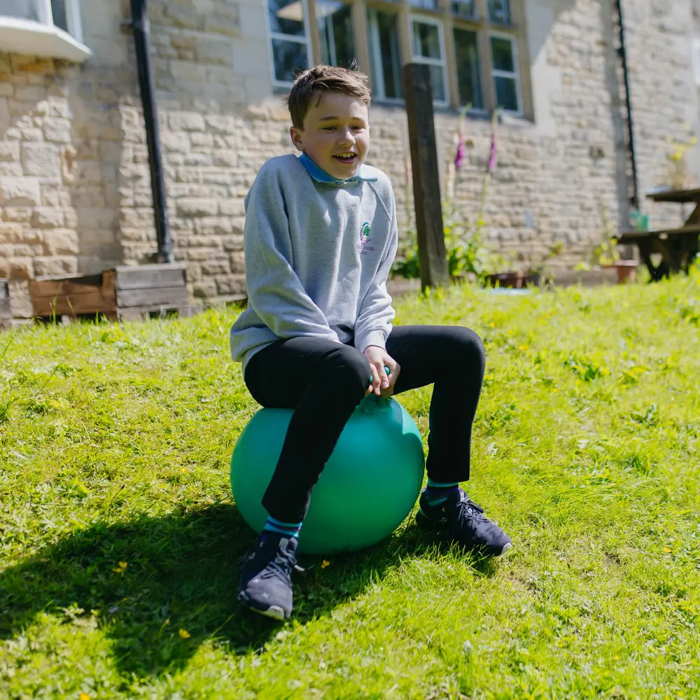 A young boy at Cedar House School playing on a space hopper outside
