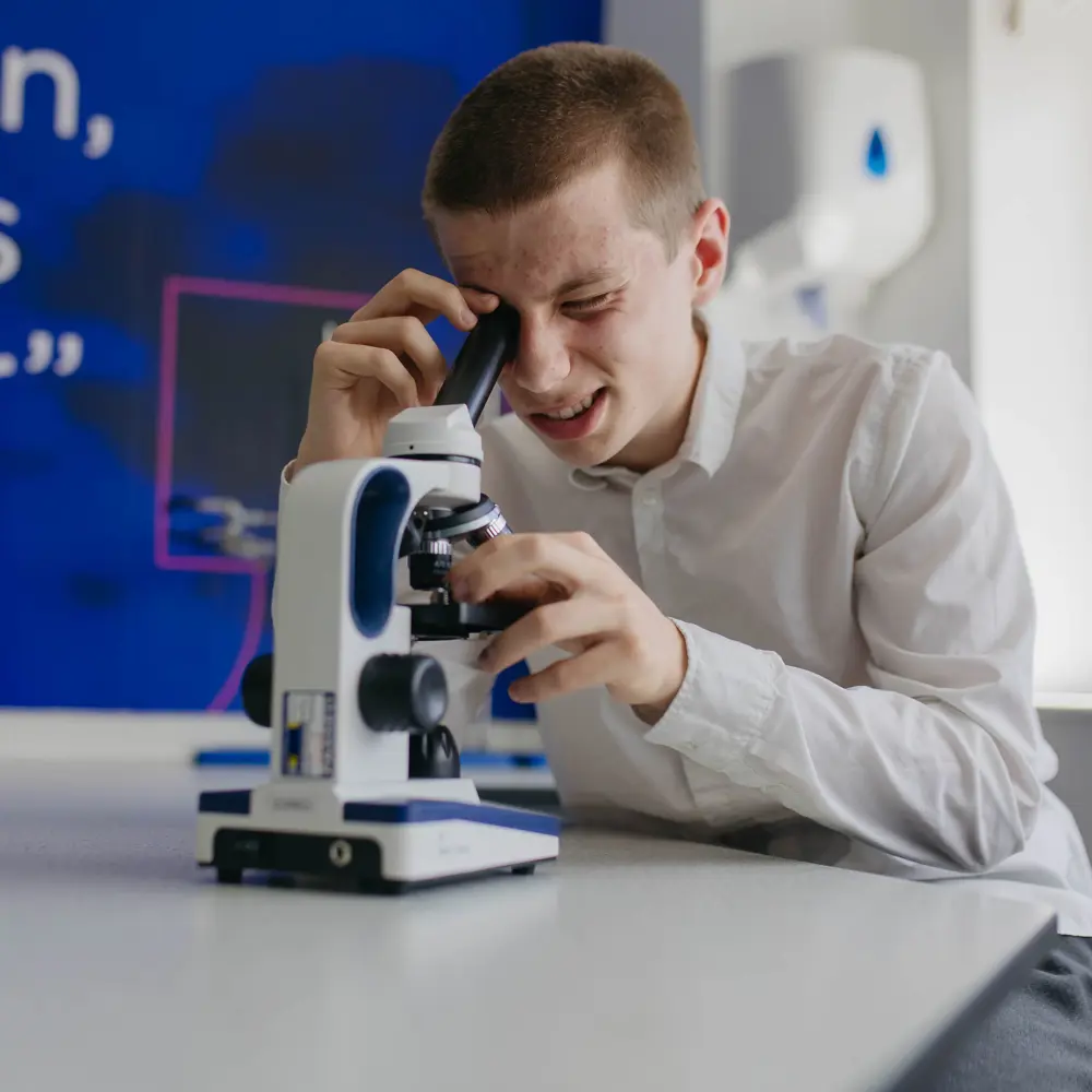 Boy looking into a microscope in the lab at Abbeywood School