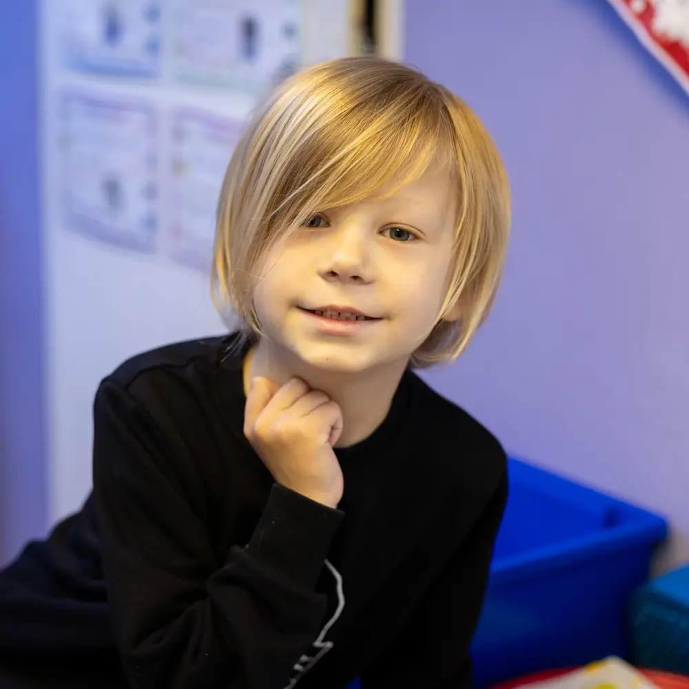 A young blonde haired boy at Lavender Lodge School smiling at the camera