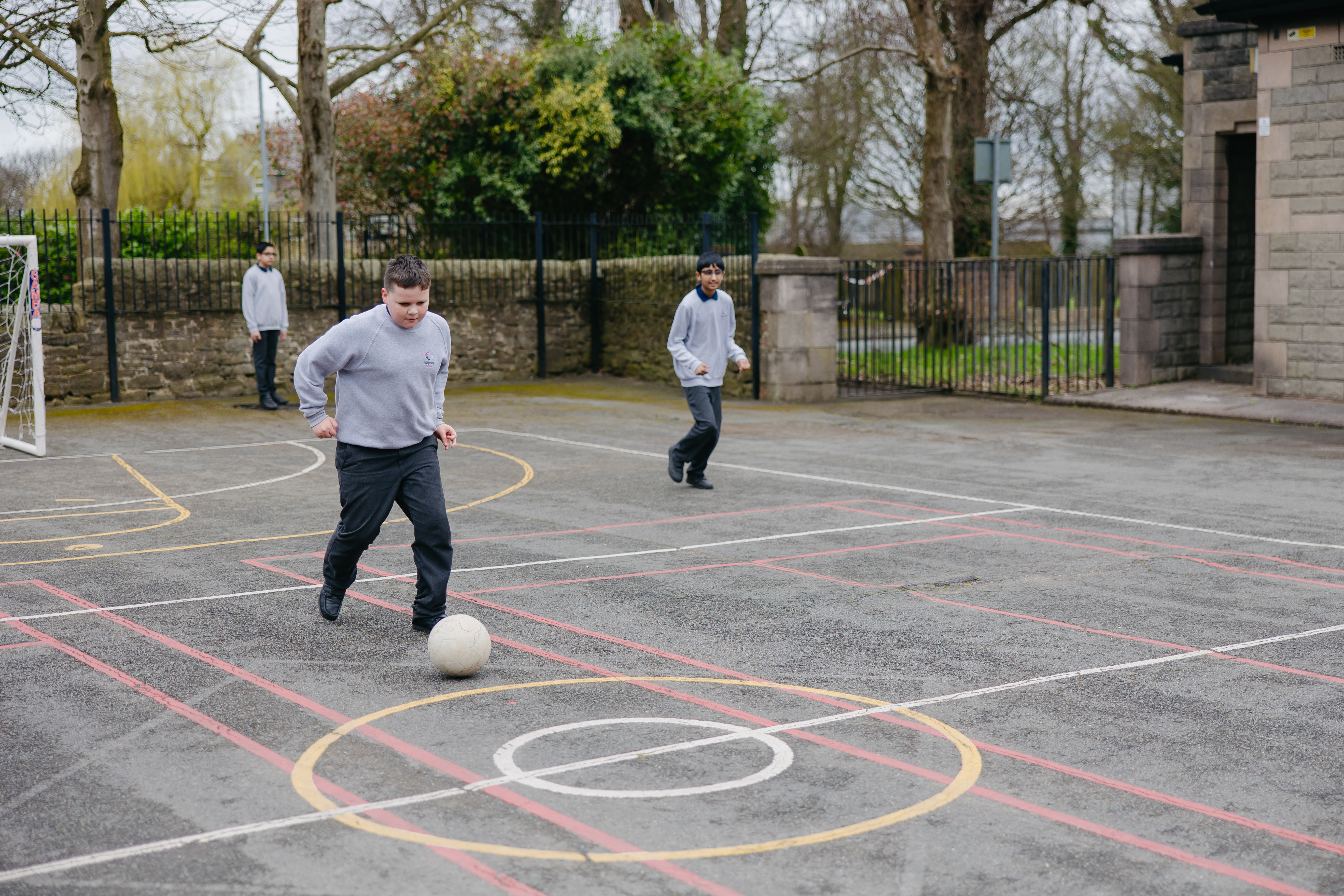 Three boys plaing football outside