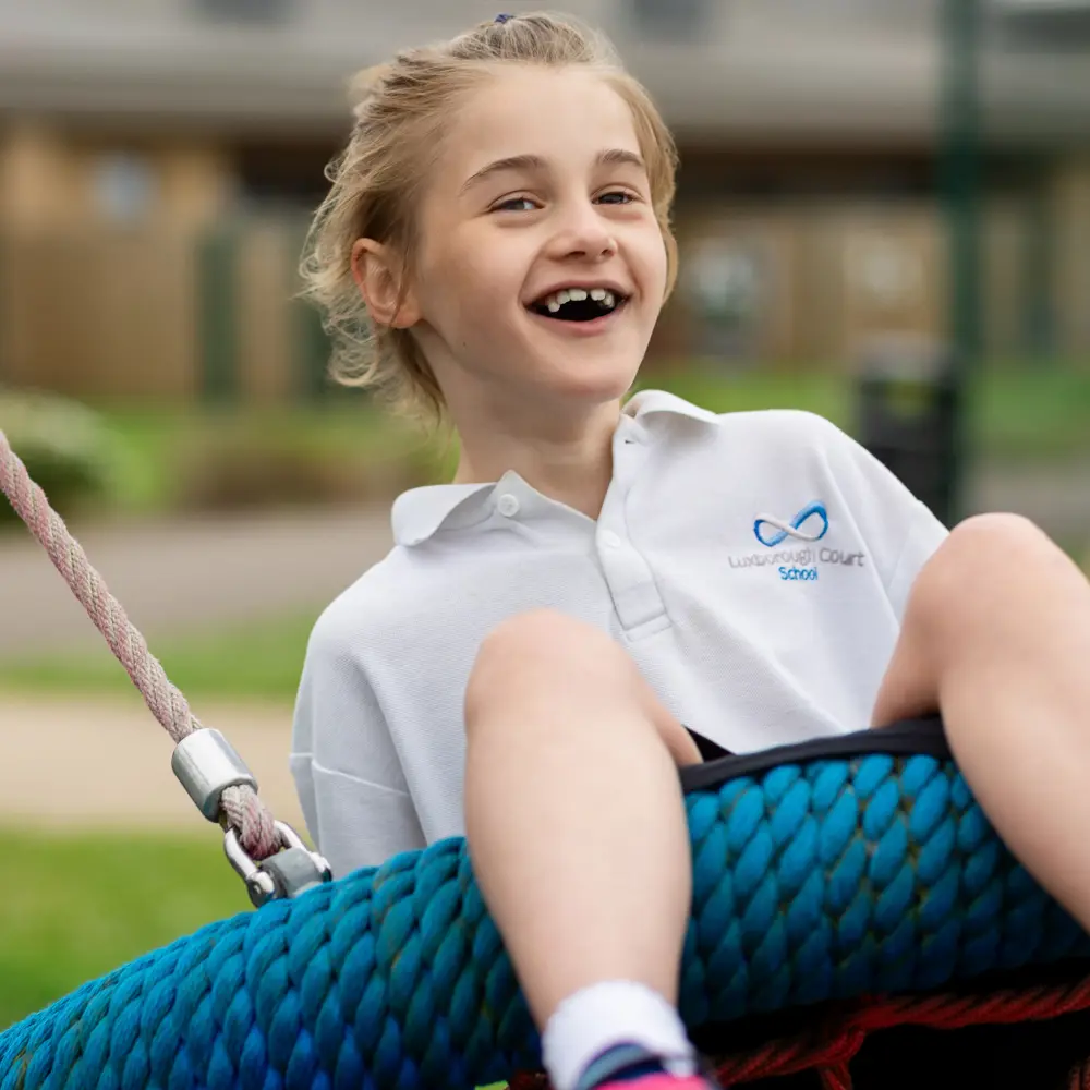 A blond haired girl from Luxborough Court School on a basket swing