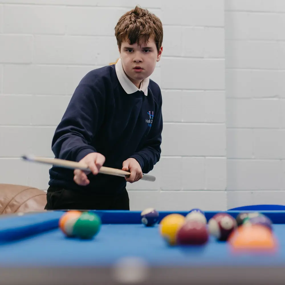 Young boy from Hall Cliffe School playing pool