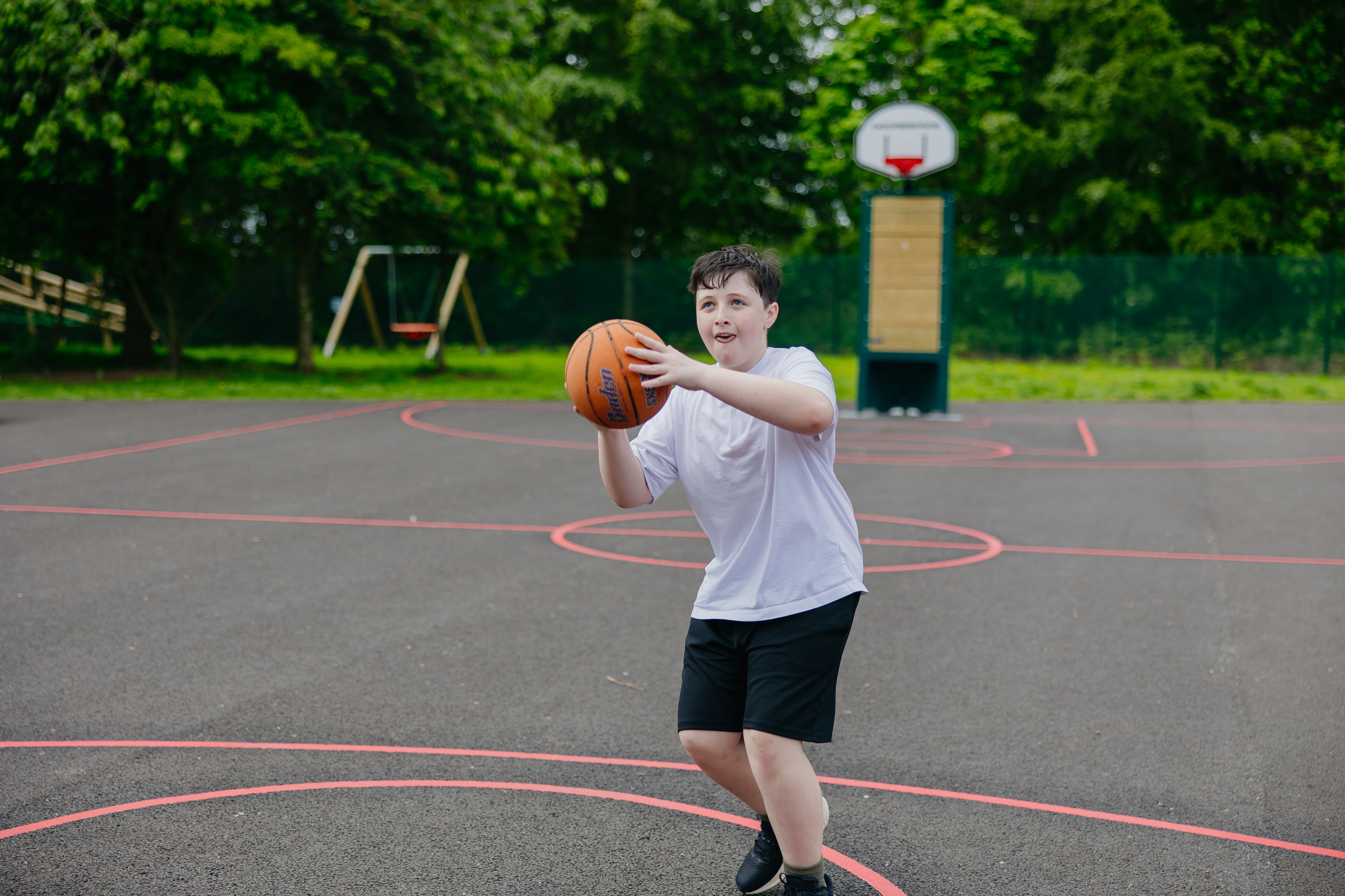 Boy on playground court about to throw a basketball
