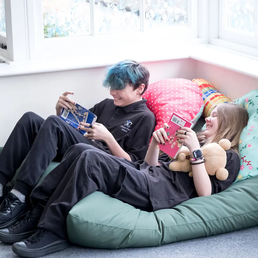Two teenagers in black uniform who are reading on beanbags