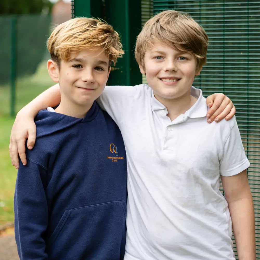 Two boys from Queensmead House School stood outside with their arms round each other