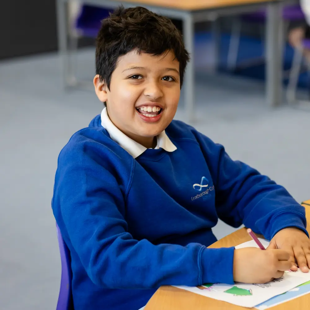 Young boy from Luxborough Court School sat at a desk smiling