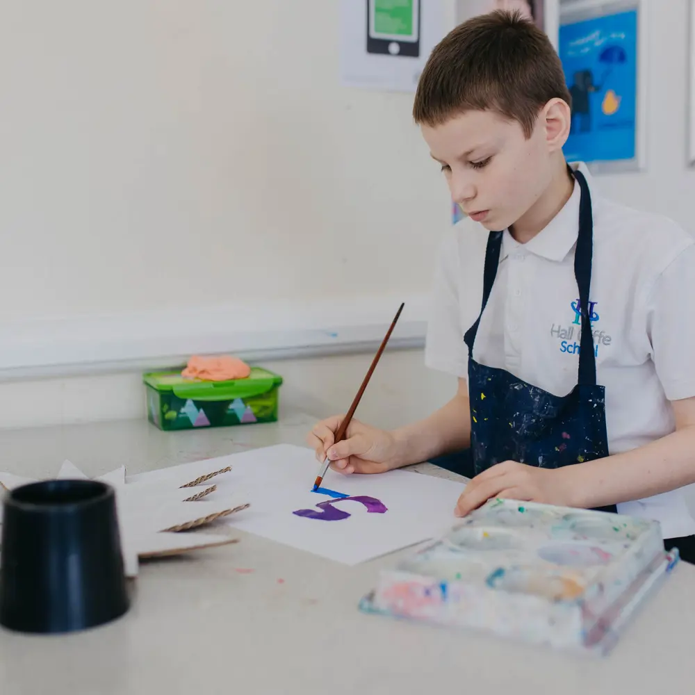A young boy with brown hair at Hall Cliffe School painting