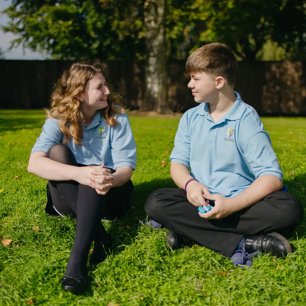 Boy and girl from Pontville School sat on the grass talking