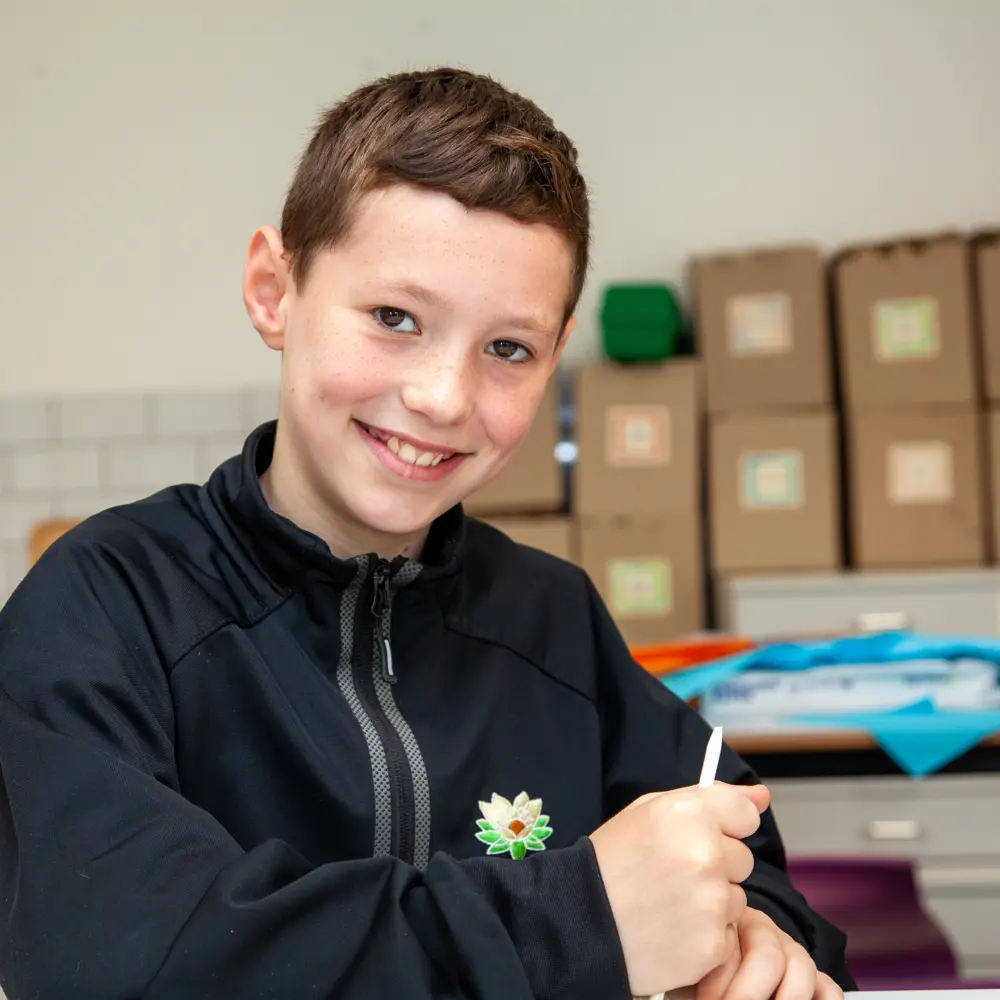 Young boy from Lakeside School sat at a desk in a classroom writing