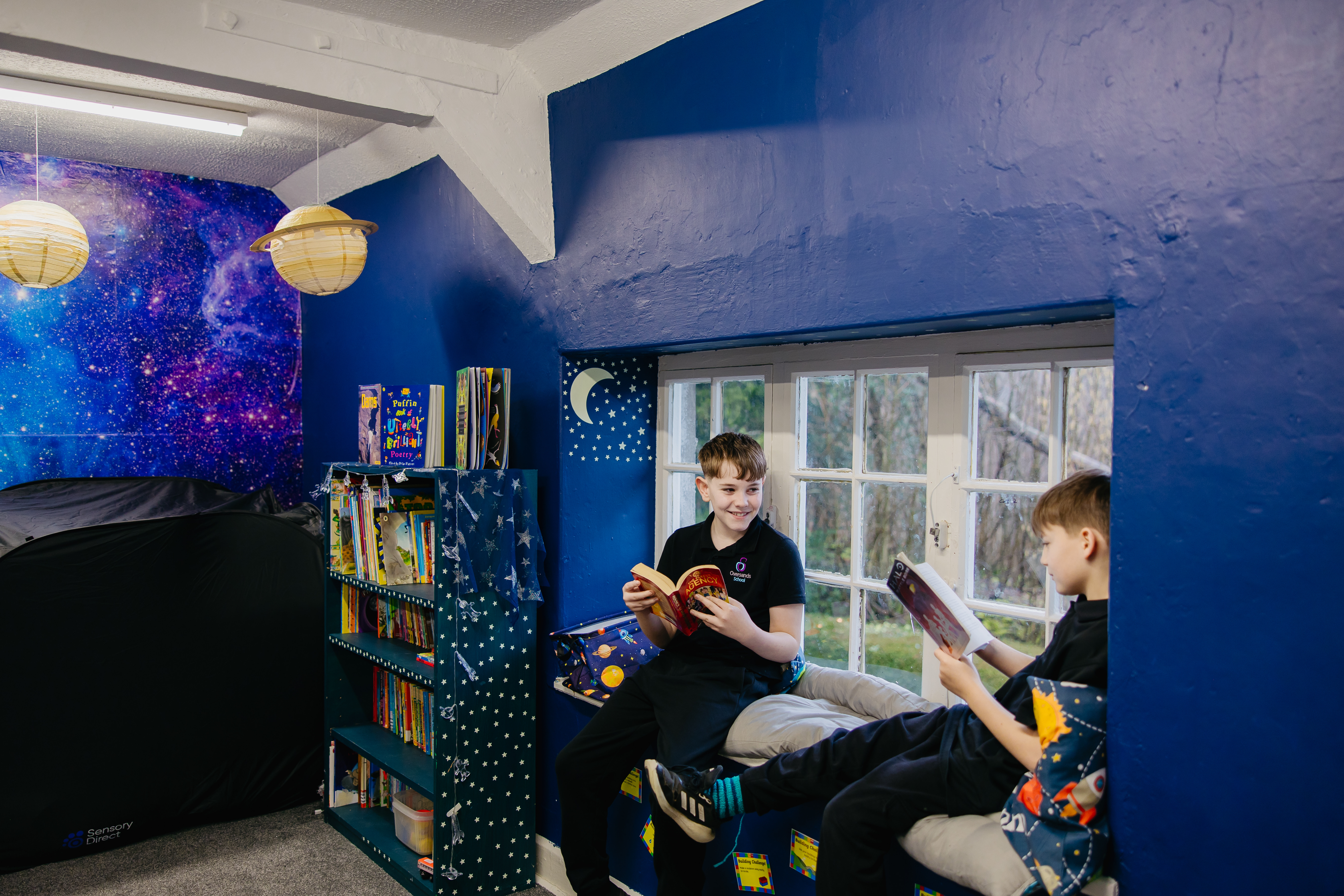 Two pupils sat in window of sensory room reading books
