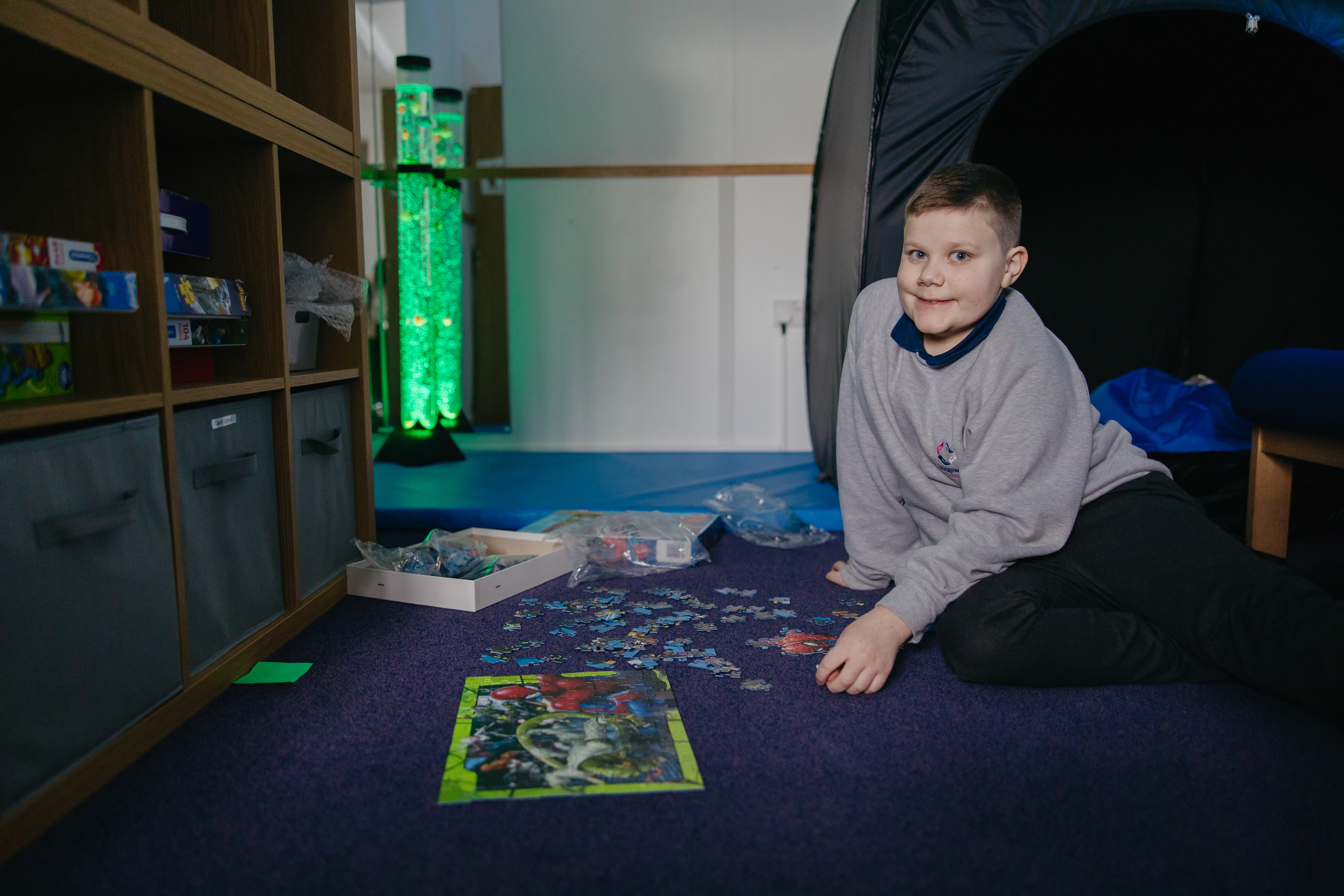 Boy playing with puzzle sat on carpet