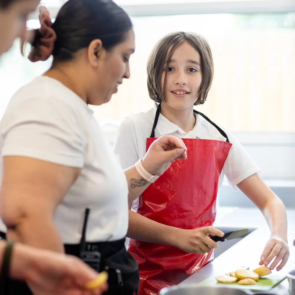 A young girl at Luxborough Court School wearing an apron in a food technology class