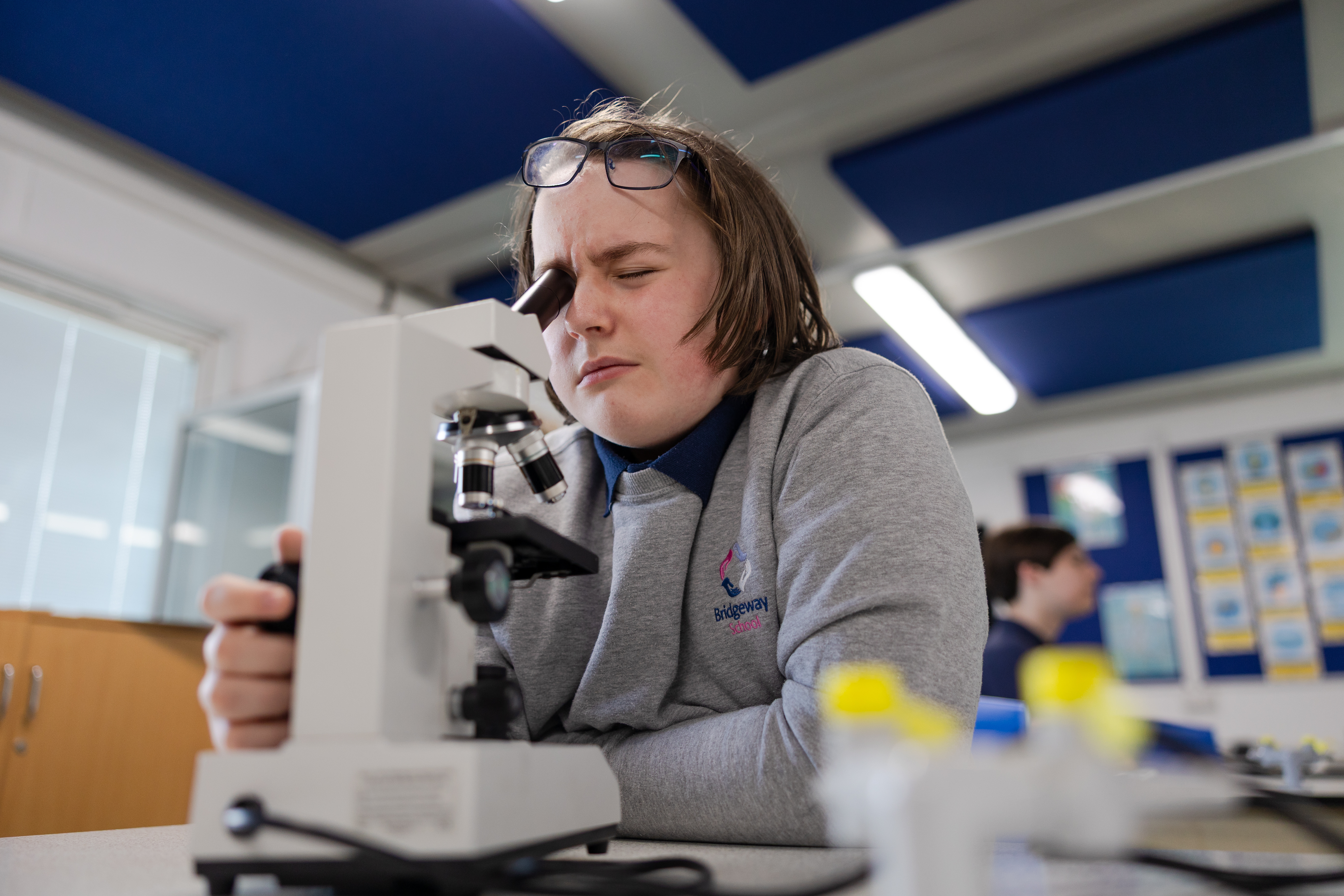 Pupil looking into micrscope in classroom