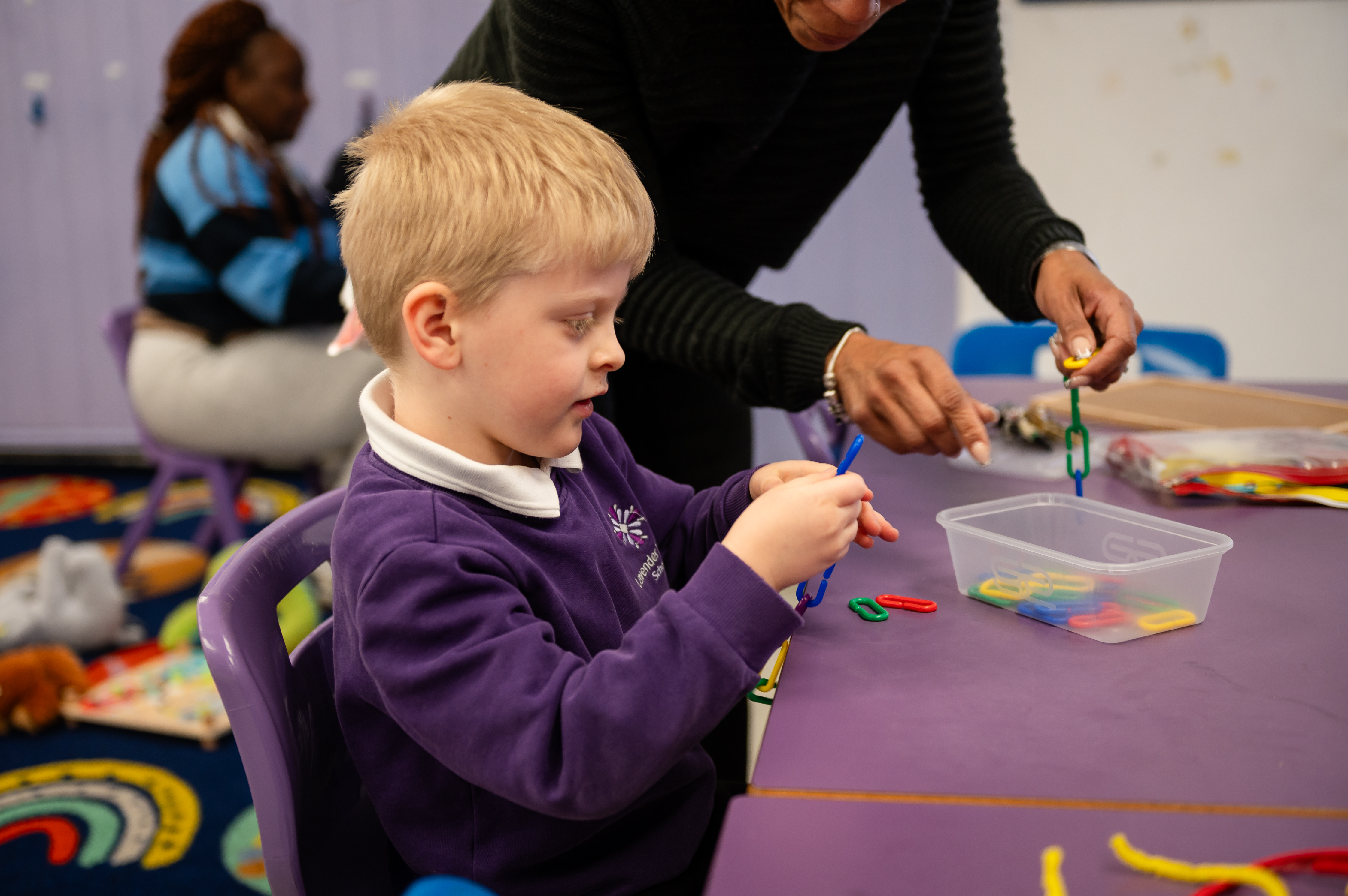 Boy with blonde hair playing with plastic shapes at school desk