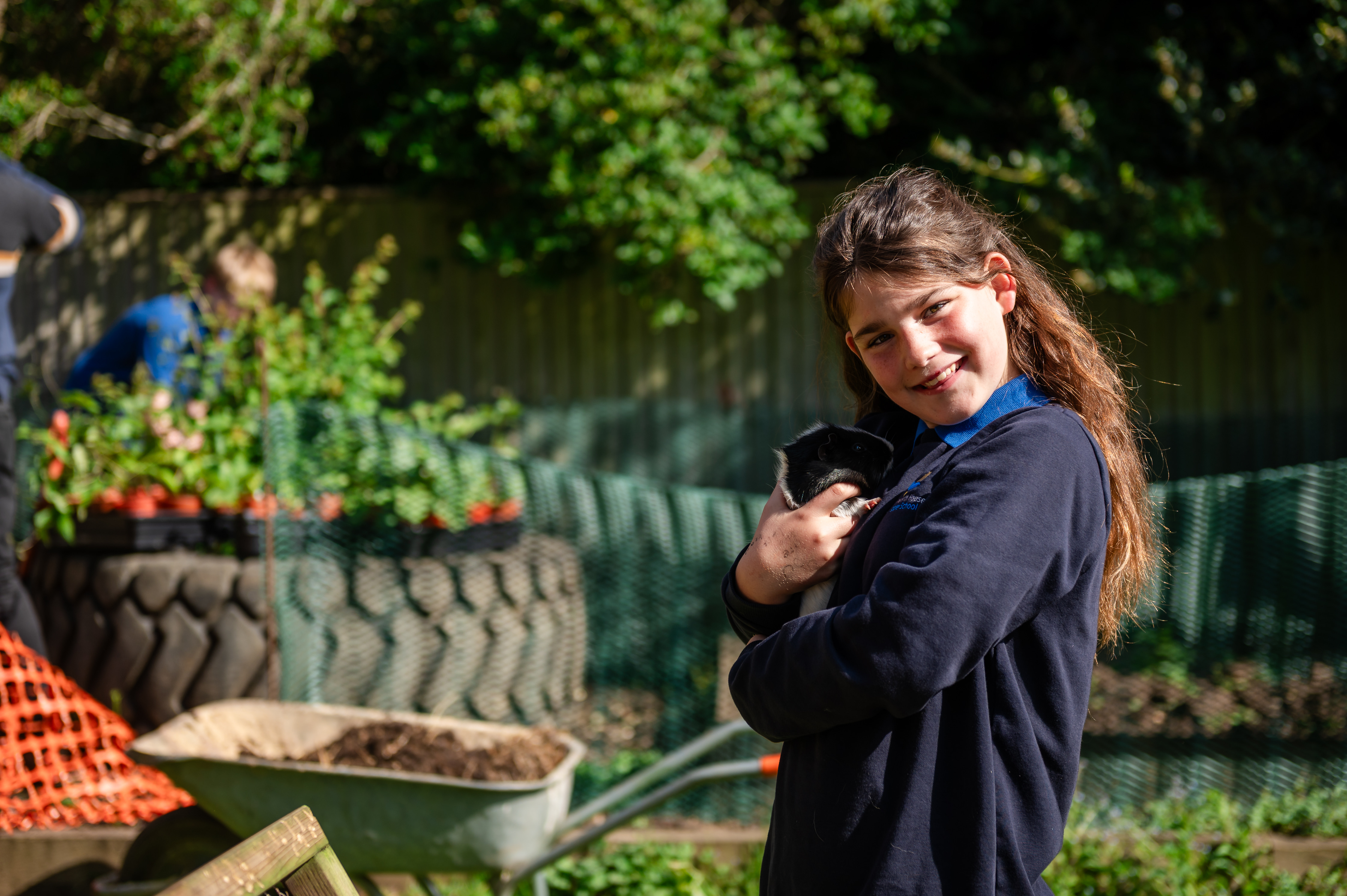 Girl stood in school gardens holding guinea pig
