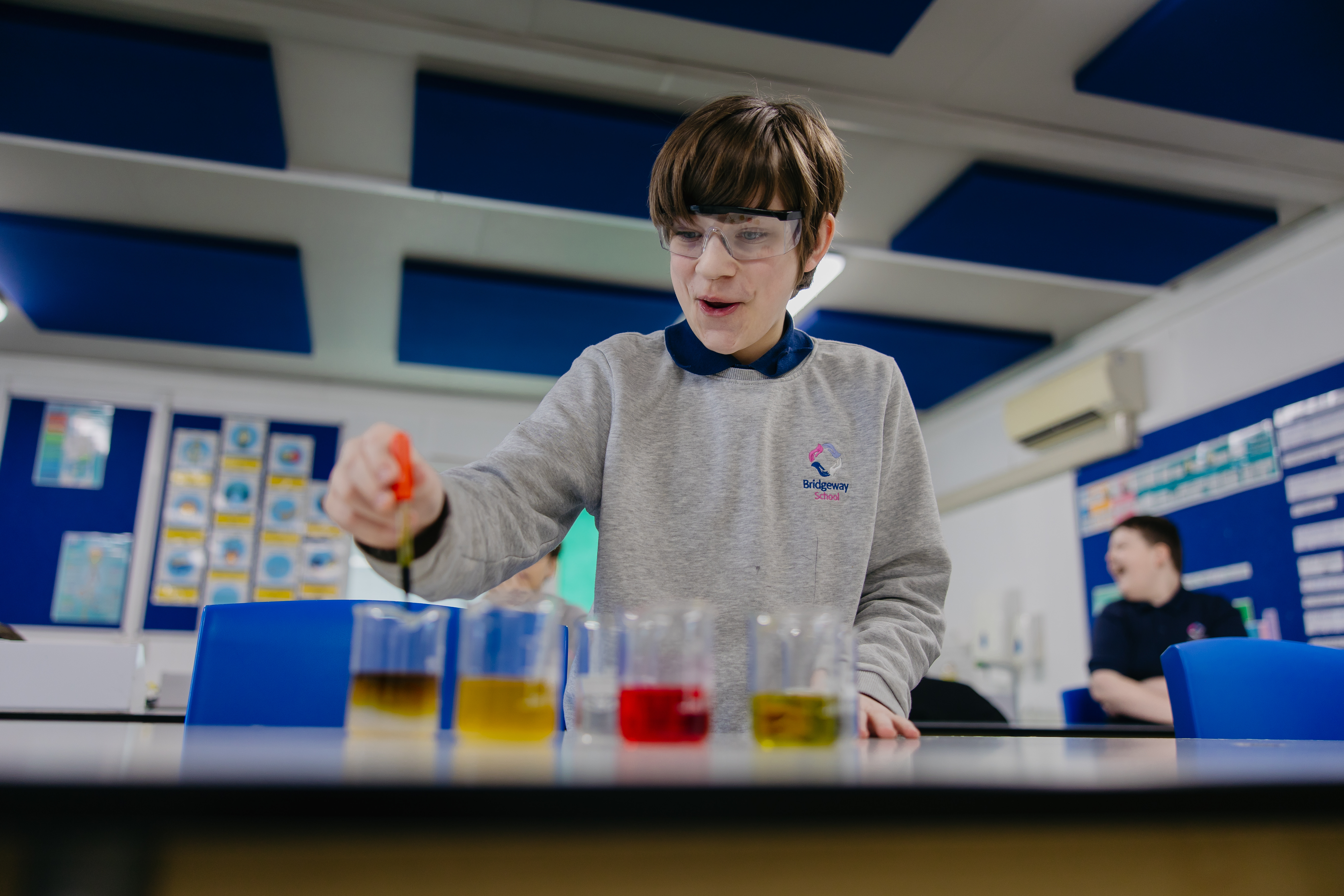 Young boy performing science experiment with test tubes and colour liquids