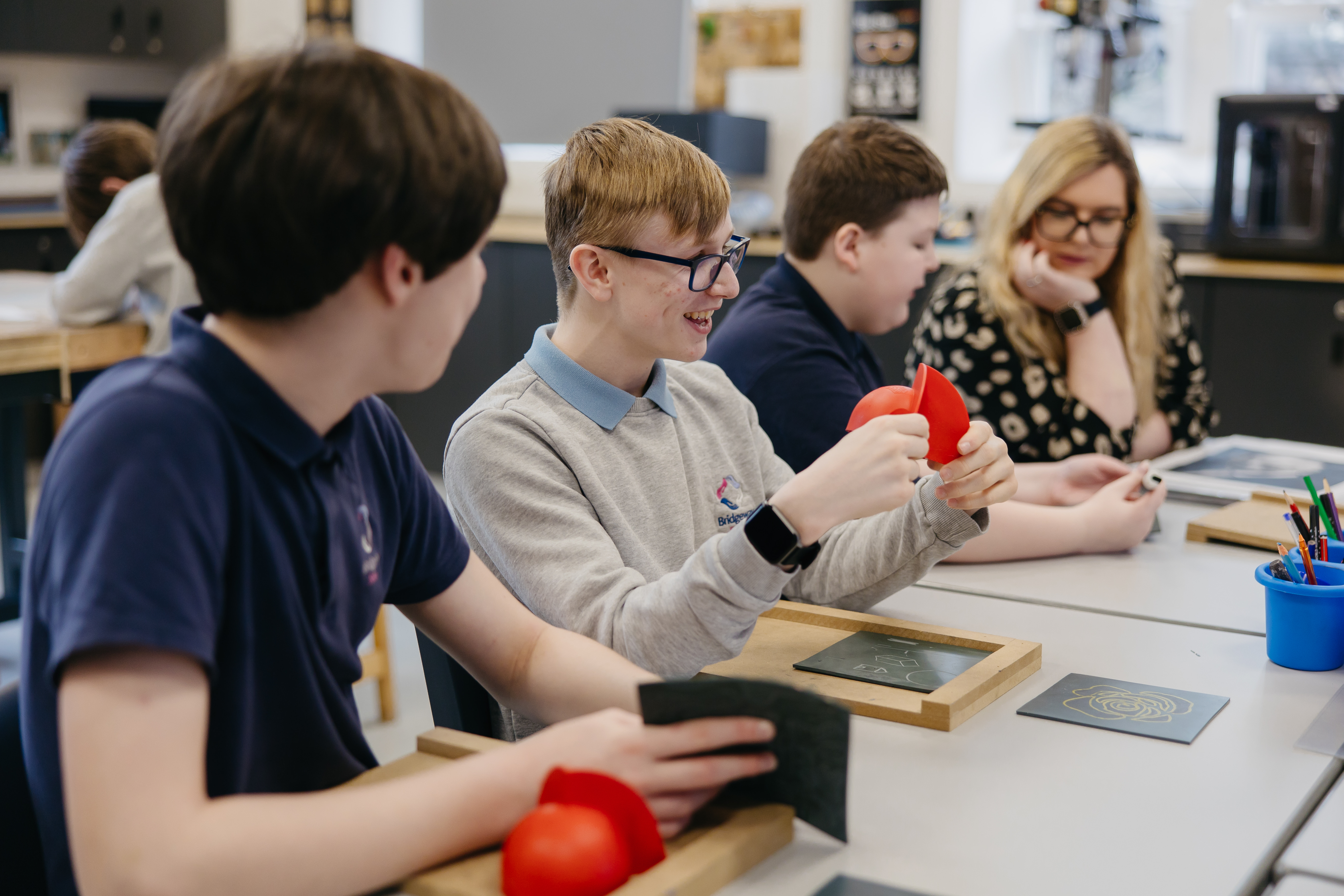 Three pupils and a teacher assistant wokring on art projects