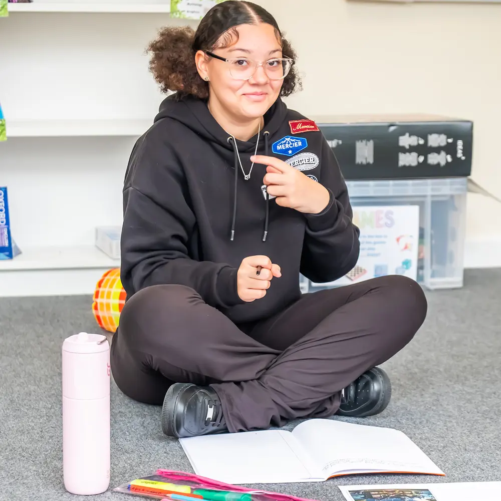 Female pupil with brown hair at Hilden Park School sat on the floor