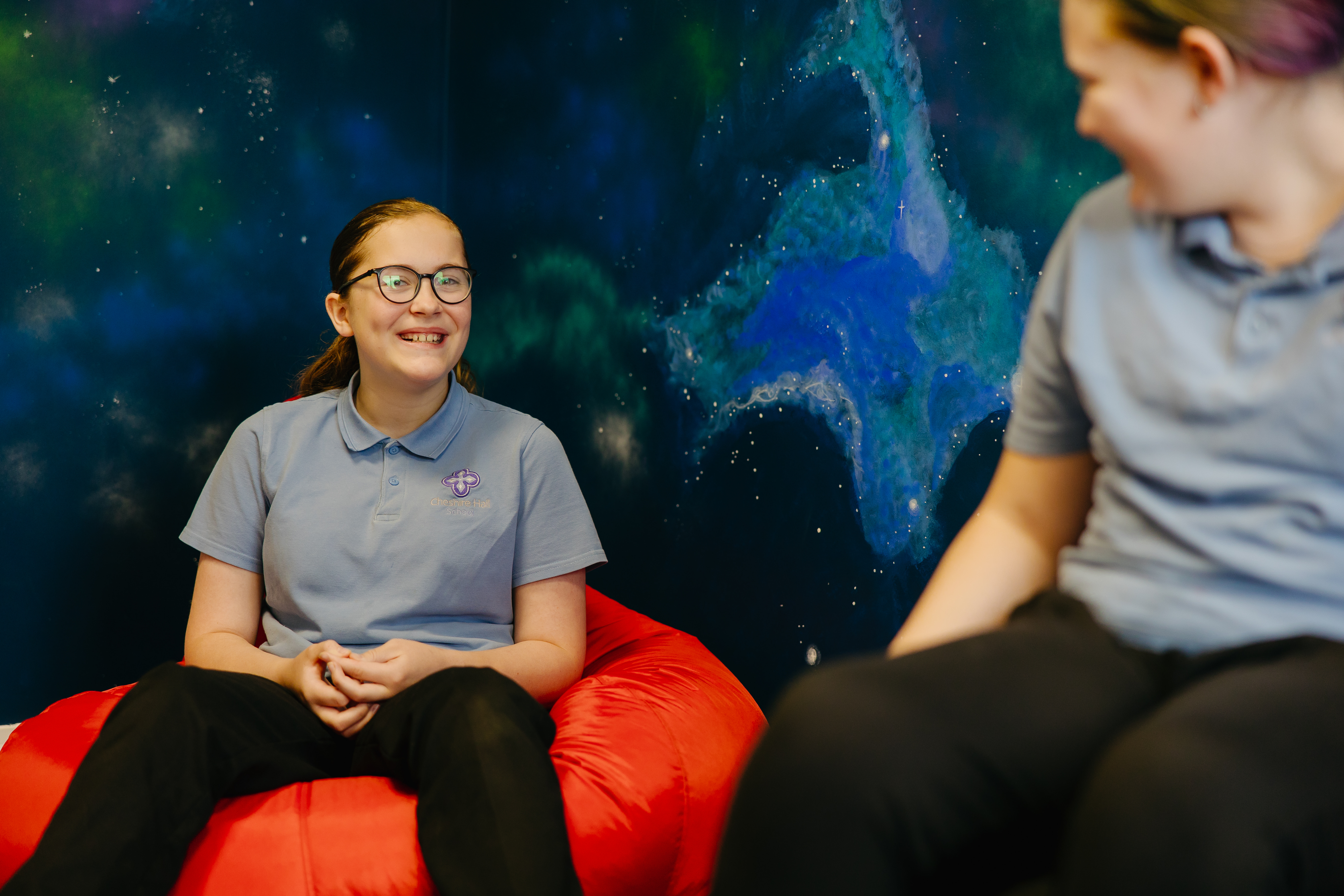 Two girls sat in sensory room on beanbags