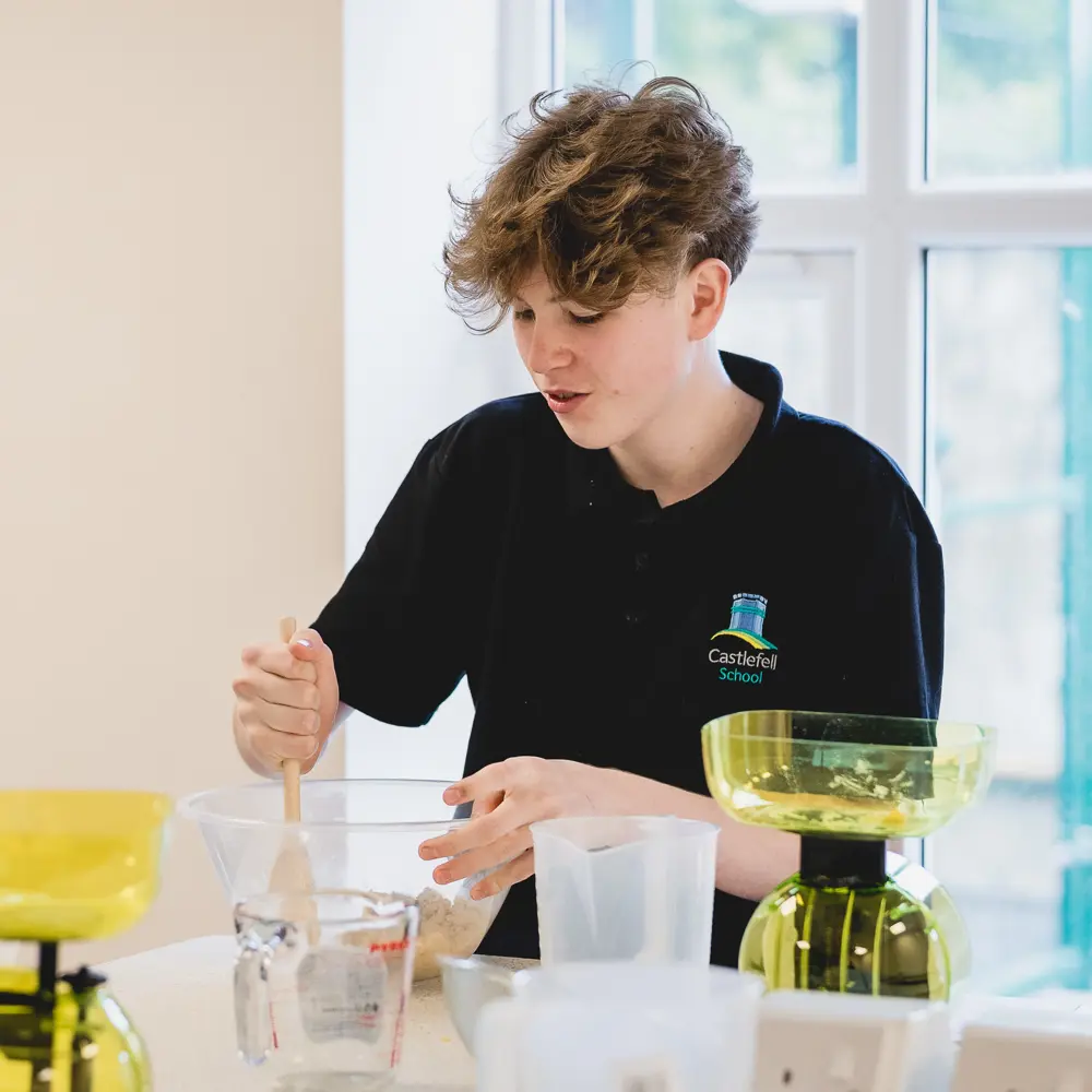 A young boy at Castlefell School mixing cooking ingredients in a bowl in food technology