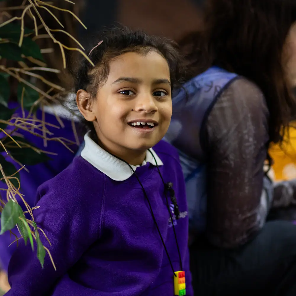 A young girl at Lavender Lodge smiling wearing a purple jumper