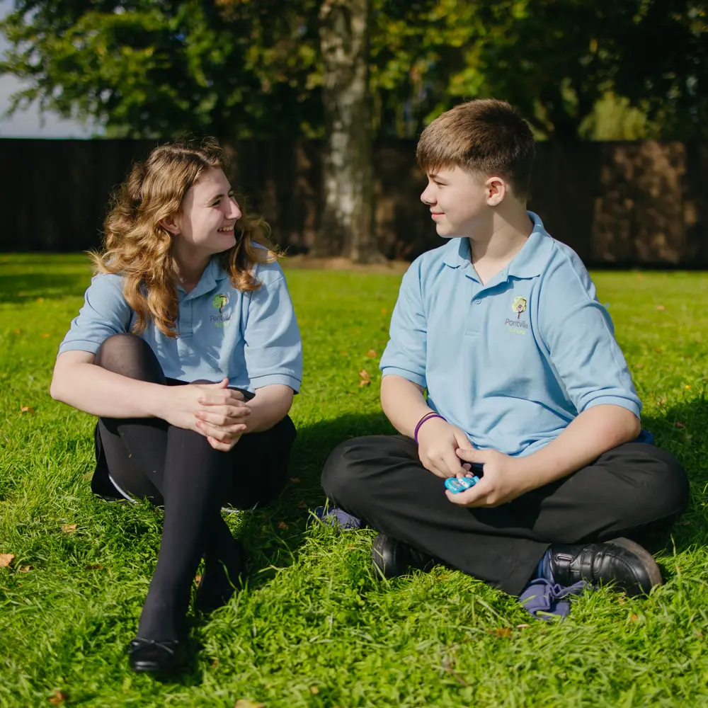 Boy and girl from Pontville School sat on the grass talking
