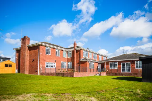 An outdoor photo of The Gables Learning Centre on a sunny day with freshly cut grass