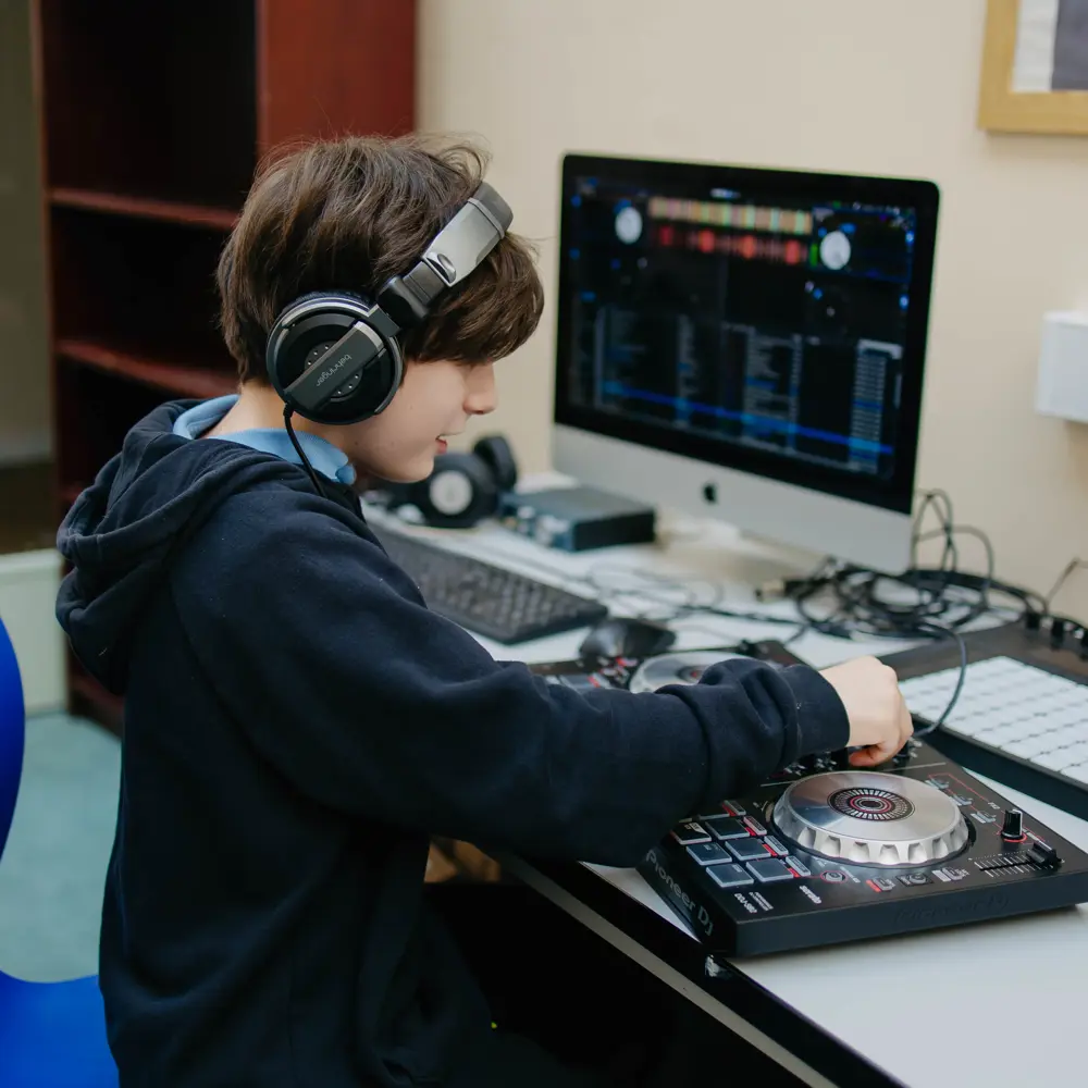 A young boy at Pontville School wearing a headset using a DJ set