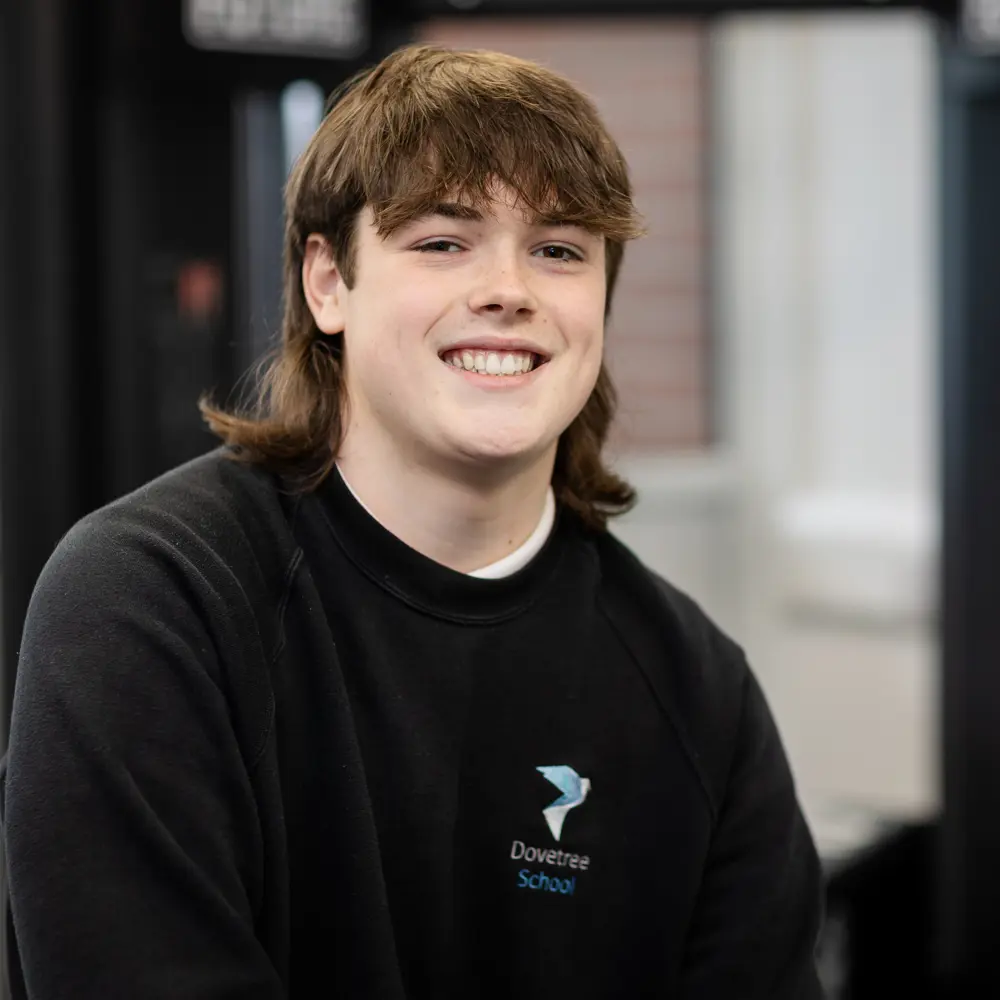 A young boy at Dovetree School smiling at the camera wearing his school uniform