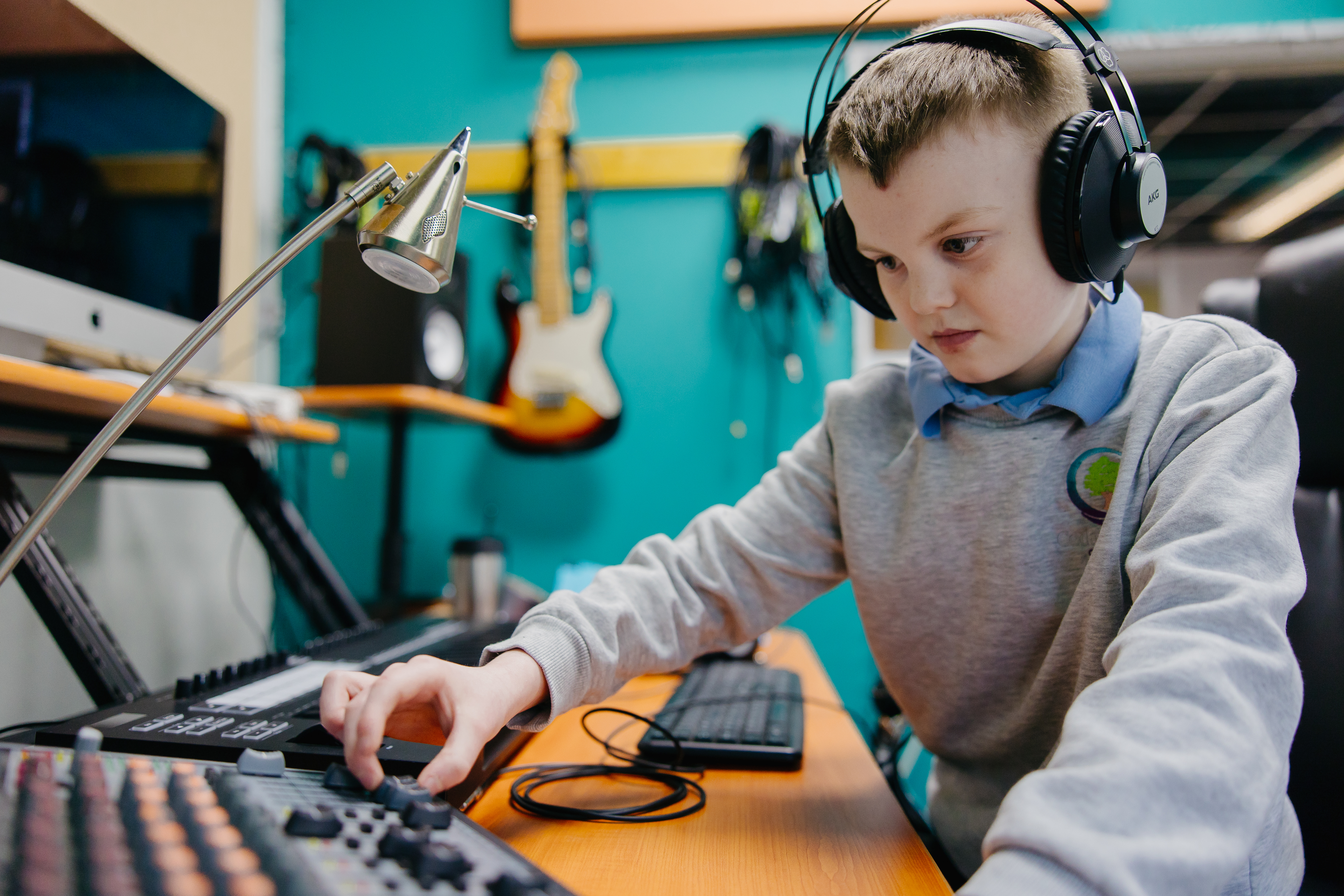 Boy wearing headphone and playing music in music studio